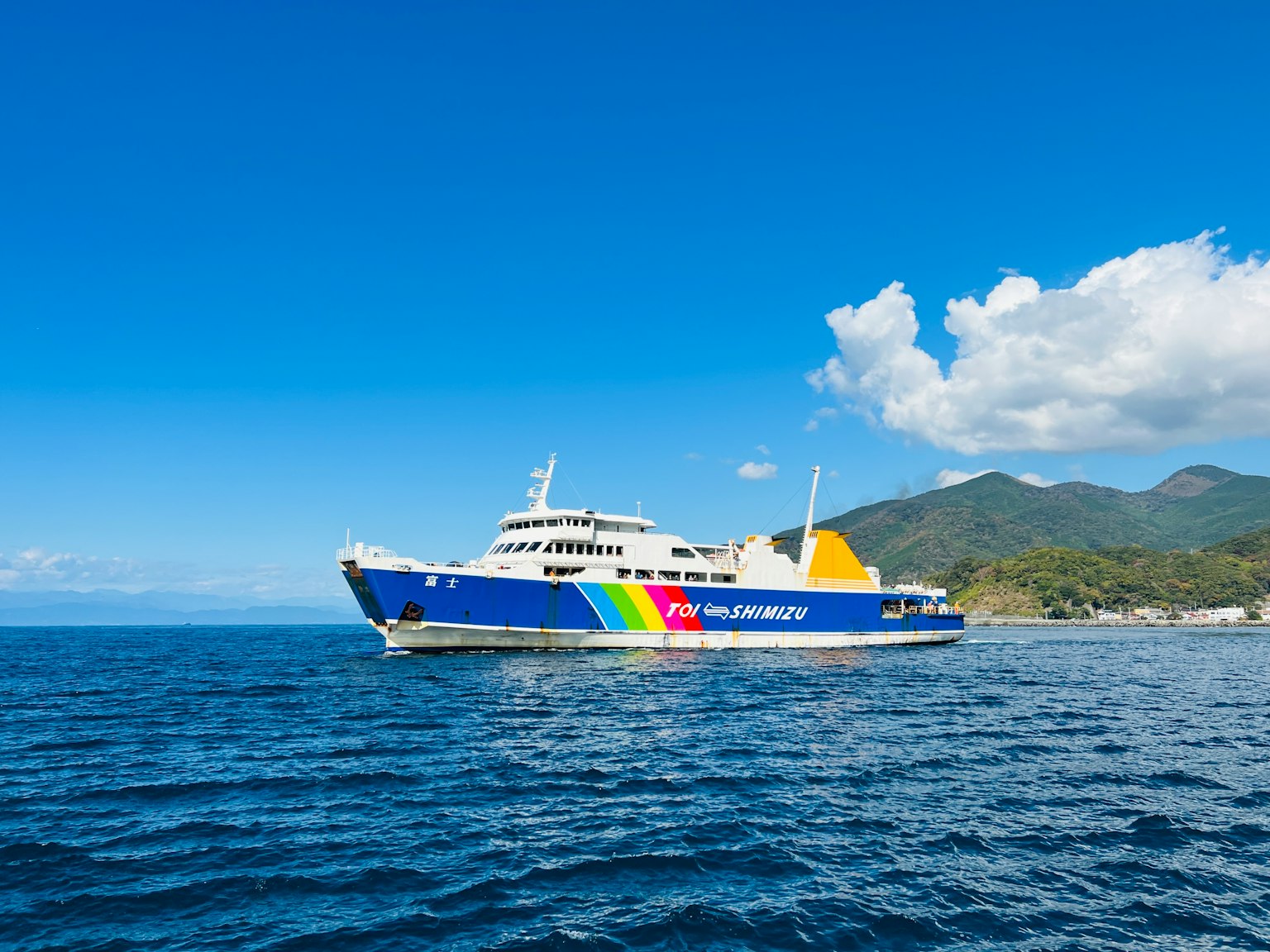Ferry colorido navegando en el mar azul bajo un cielo despejado