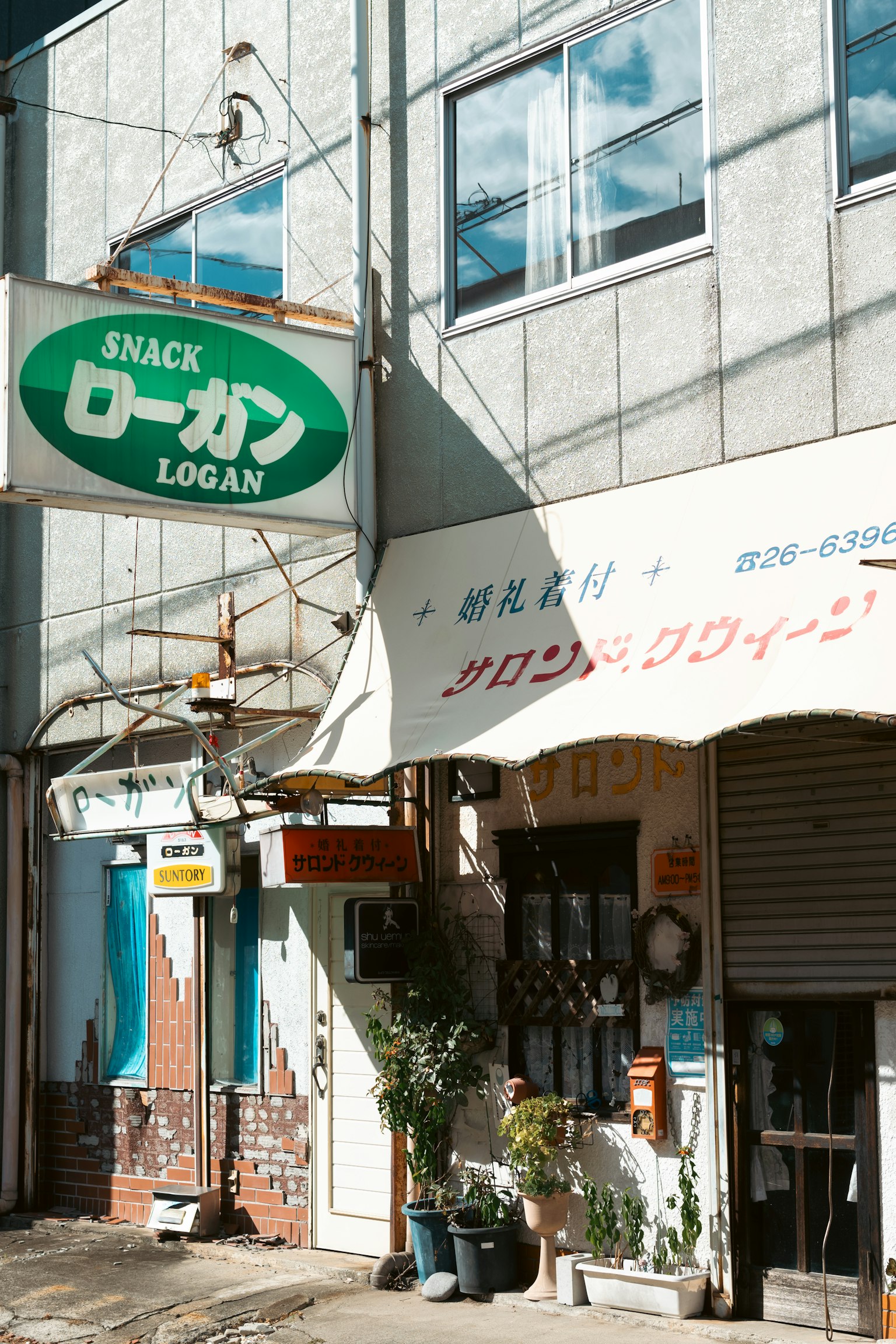 Eksterior dari bar camilan retro bernama Logan dengan tanda hijau dan arsitektur tradisional Jepang