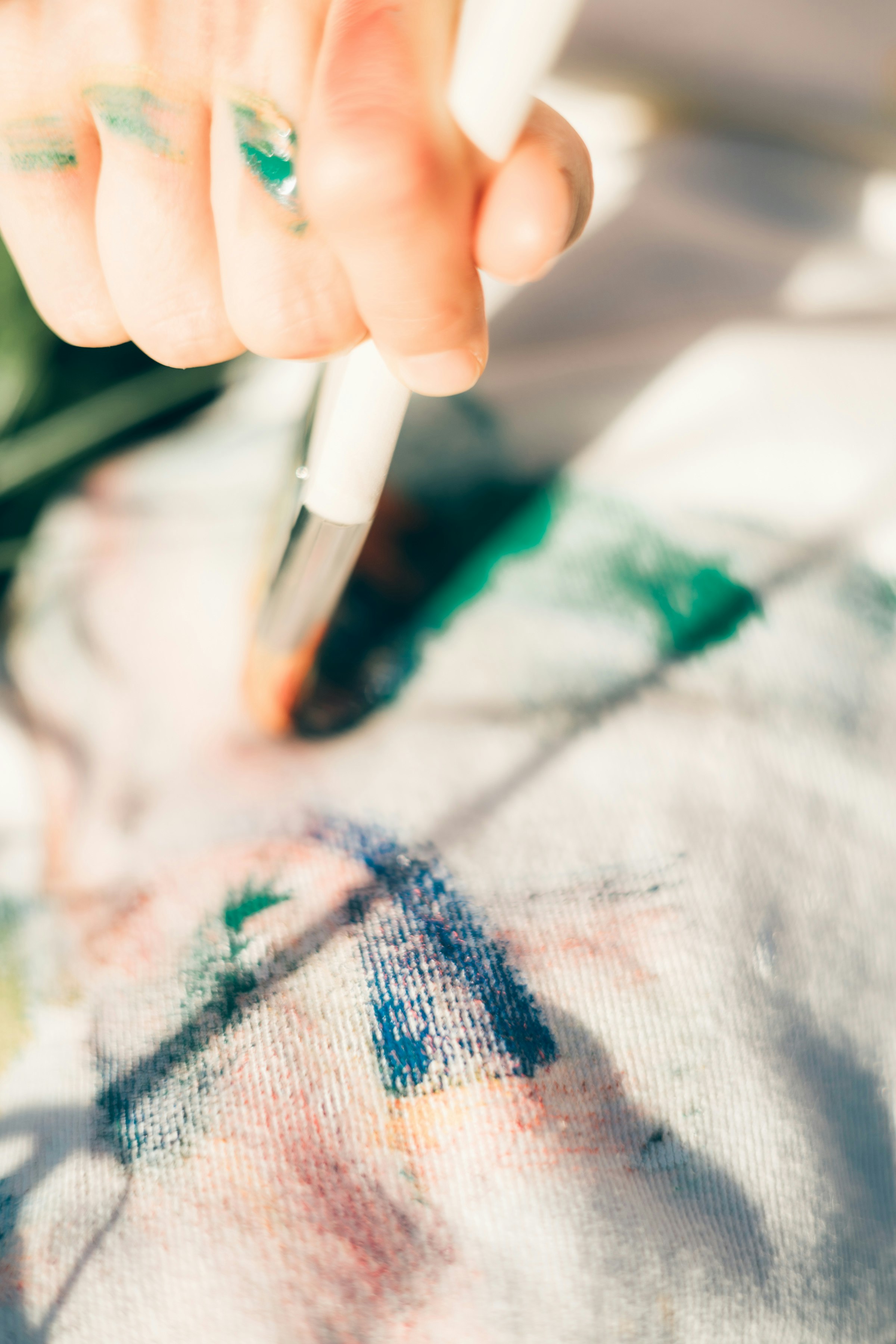 絵の具で塗られたキャンバスに筆を入れる手元