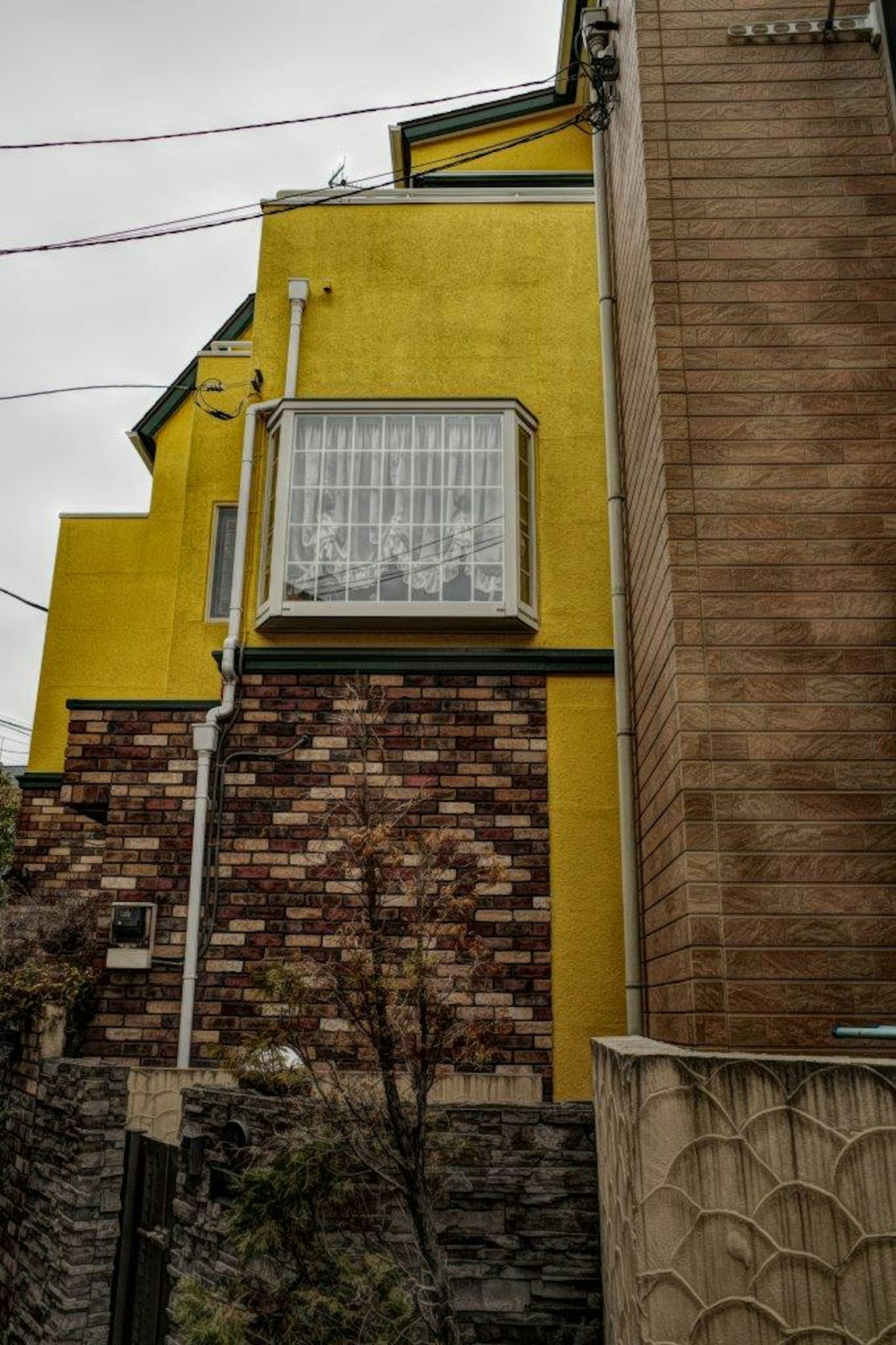 Une maison avec un mur jaune et un extérieur en brique