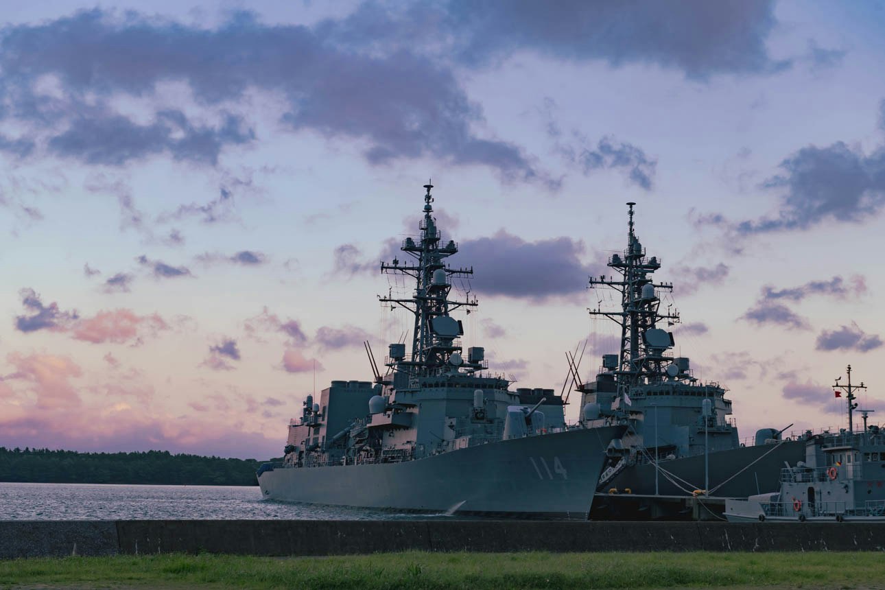 Silhouette eines Kriegsschiffs in der Dämmerung an der Küste