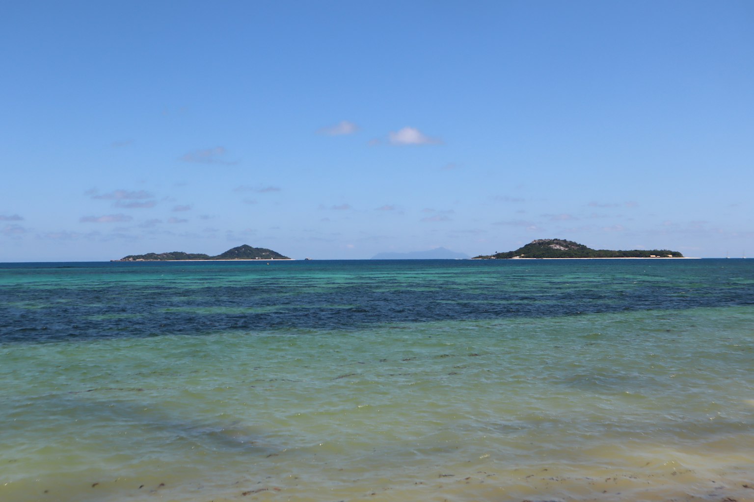 Eine schöne Strandszene mit kleinen Inseln zwischen dem blauen Ozean und dem Himmel sichtbar