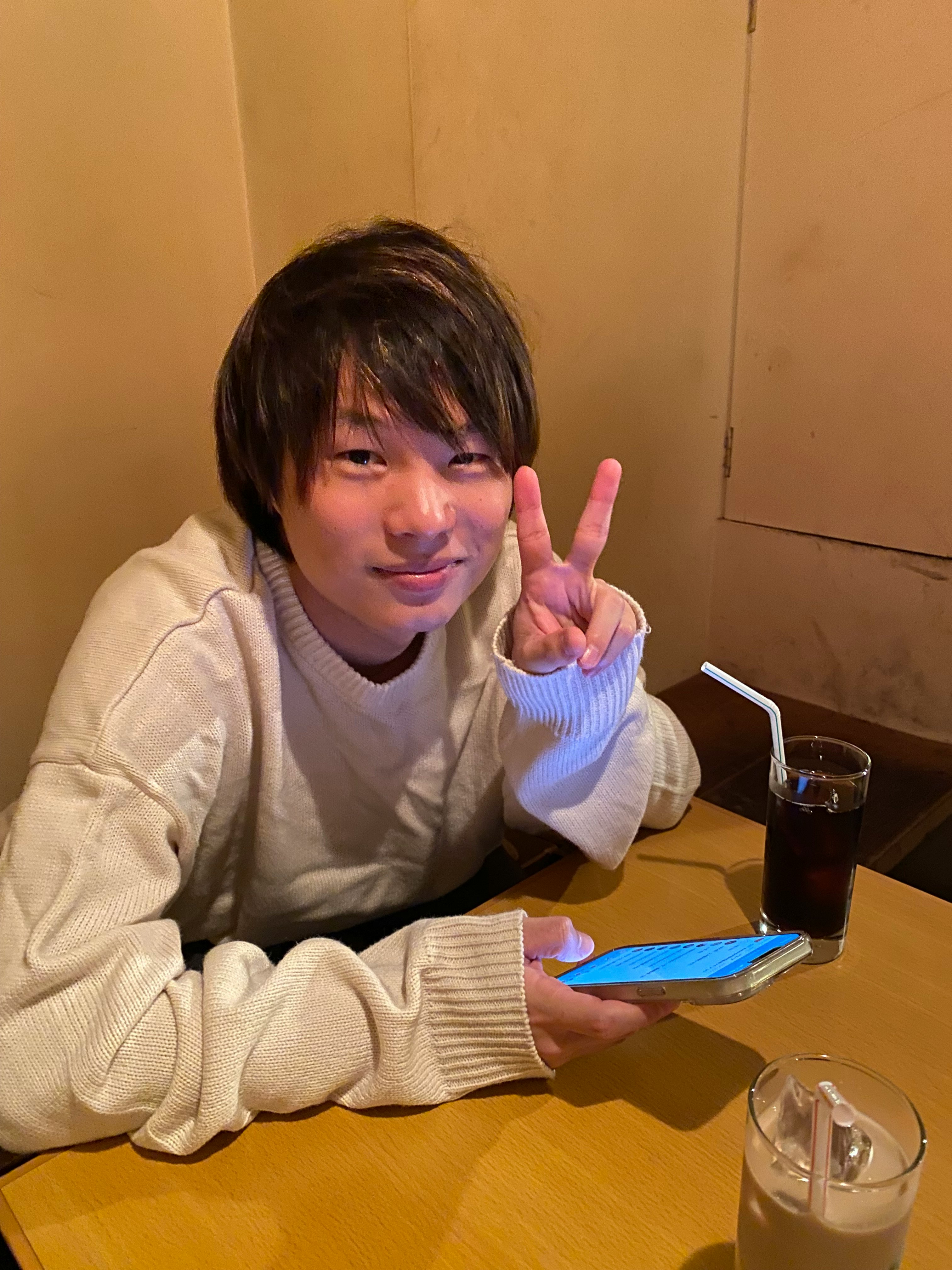 uomo che fa il segno della pace guardando il telefono a tavola