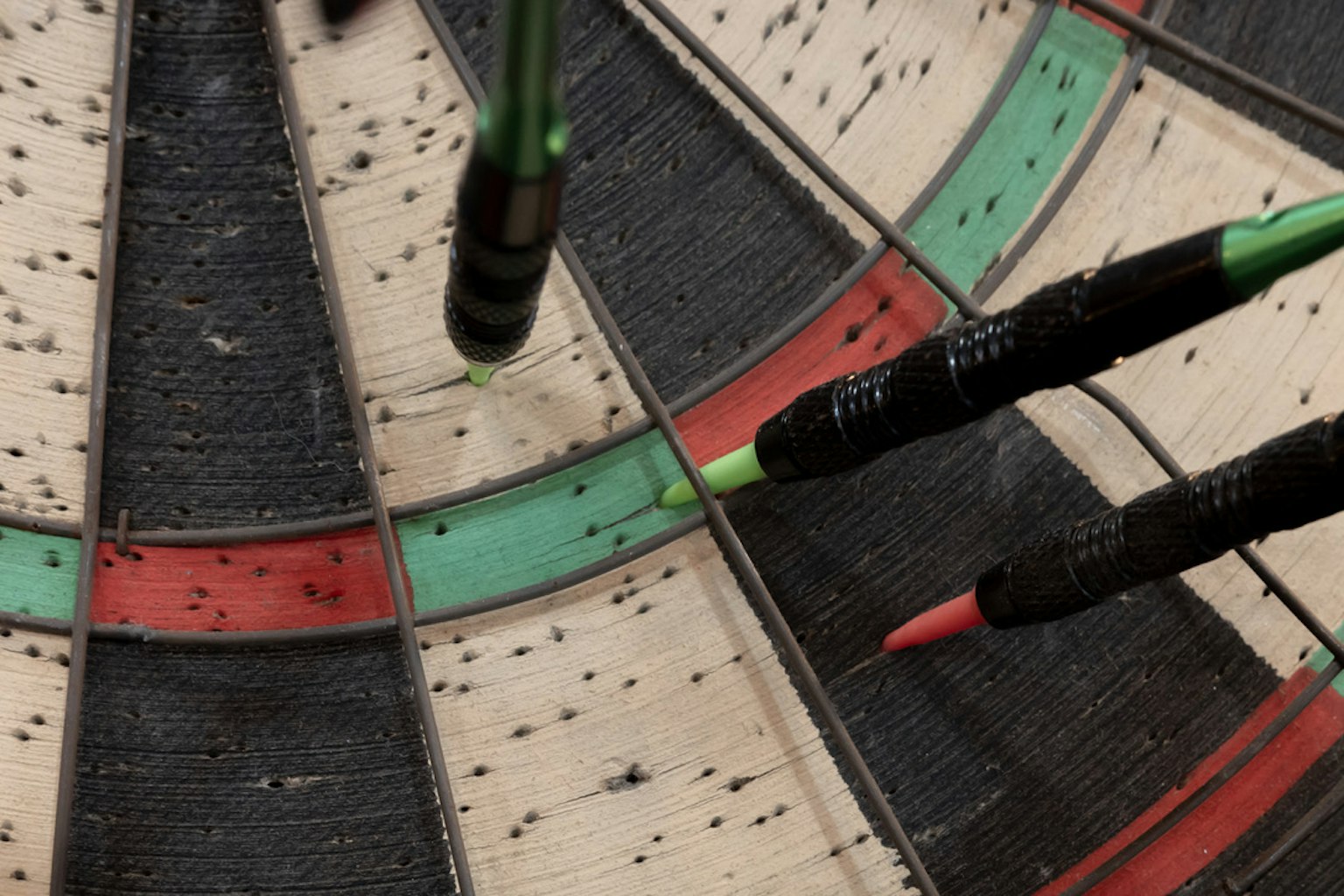 Nahaufnahme von Pfeilen, die in eine Dartscheibe mit grünen und roten Abschnitten gesteckt sind