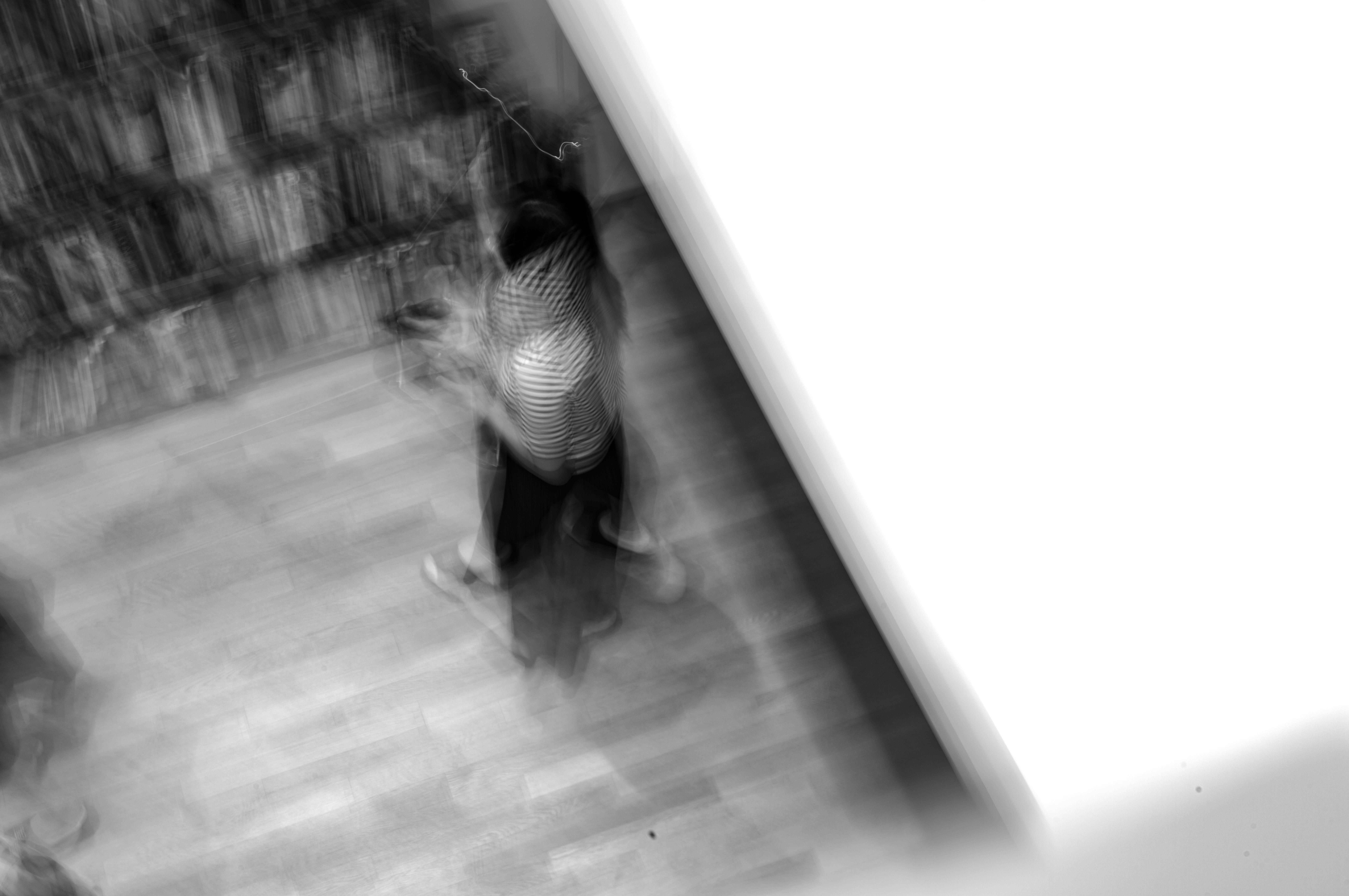 モノクロの室内で動く人影のある通路のような構図