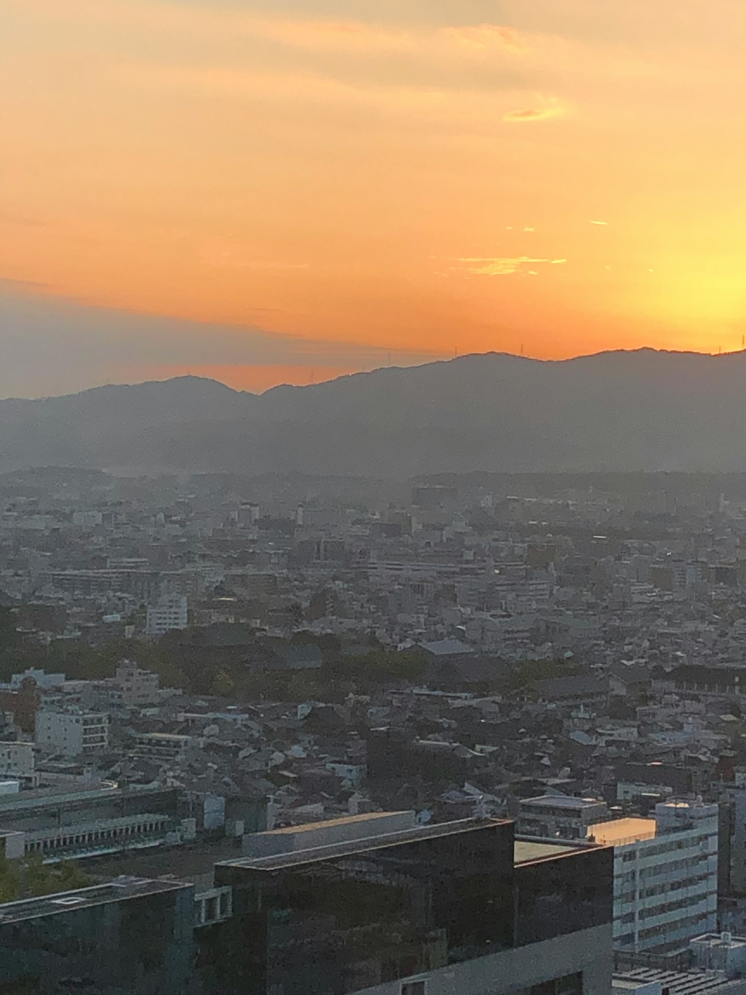 Vista panoramica di una città al tramonto con montagne sullo sfondo