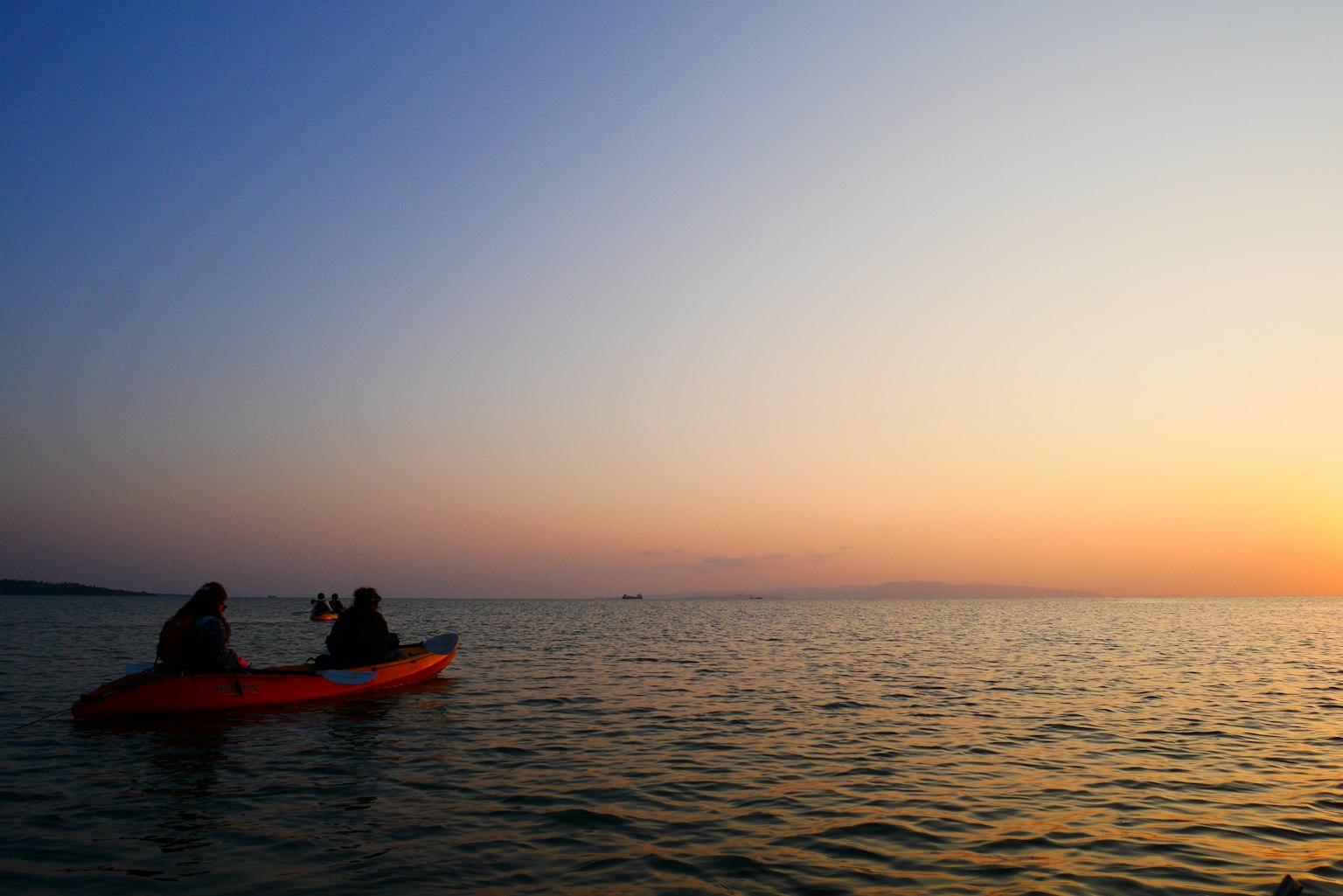 Hai người chèo thuyền kayak vào lúc hoàng hôn trên mặt nước yên tĩnh