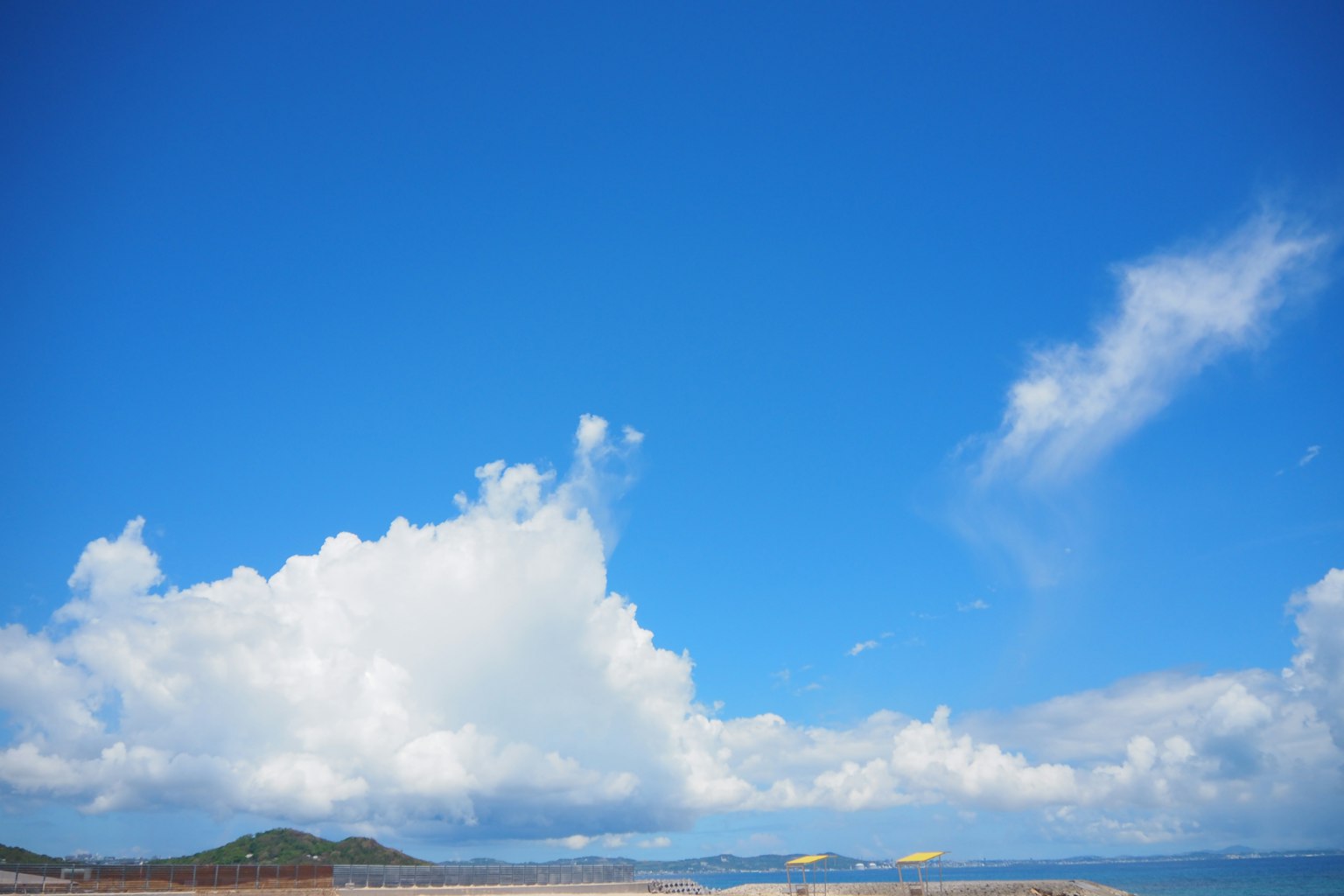 A landscape featuring a blue sky and white clouds