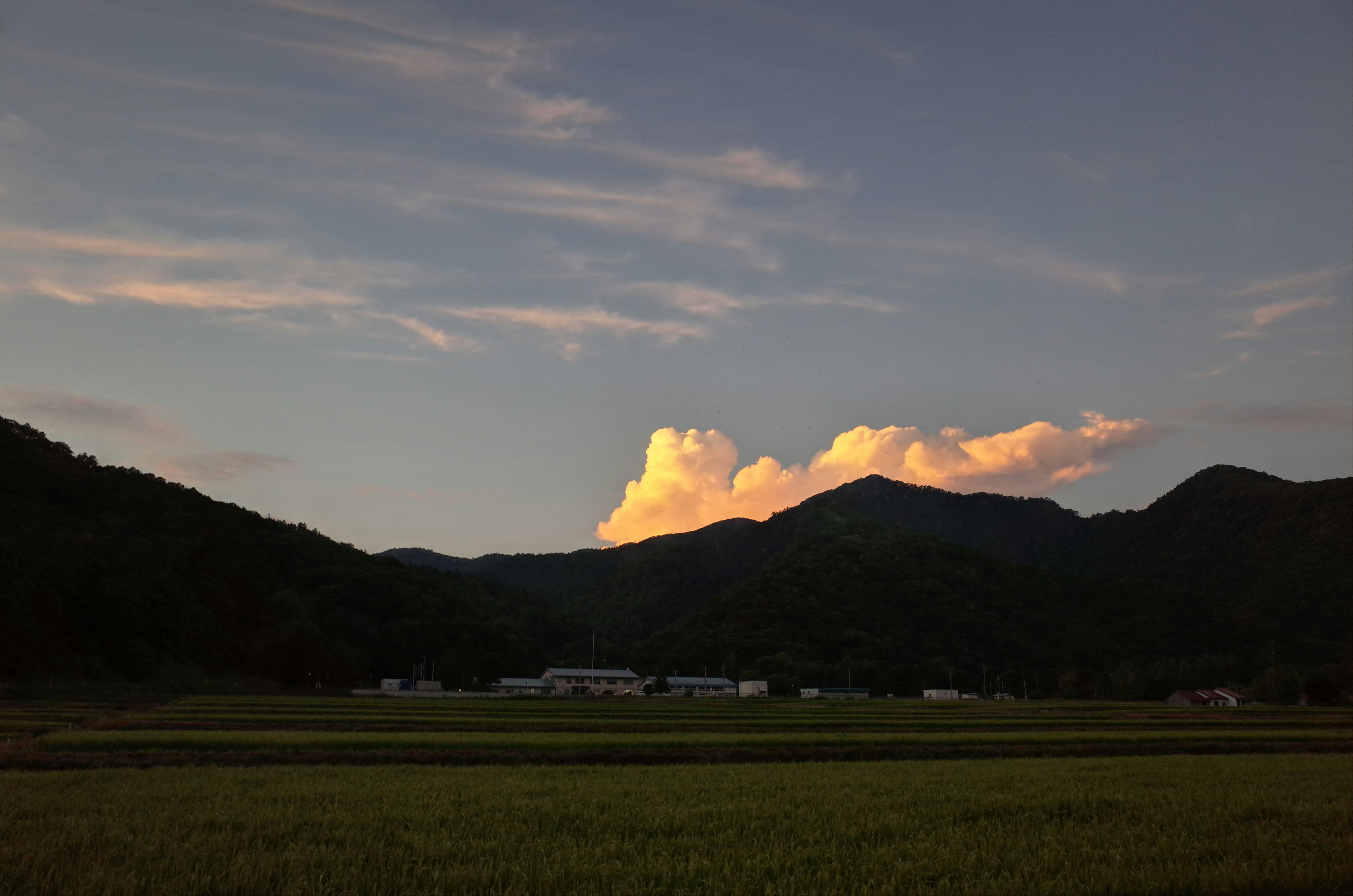 夕暮れの広い草原と山並み、雲の光