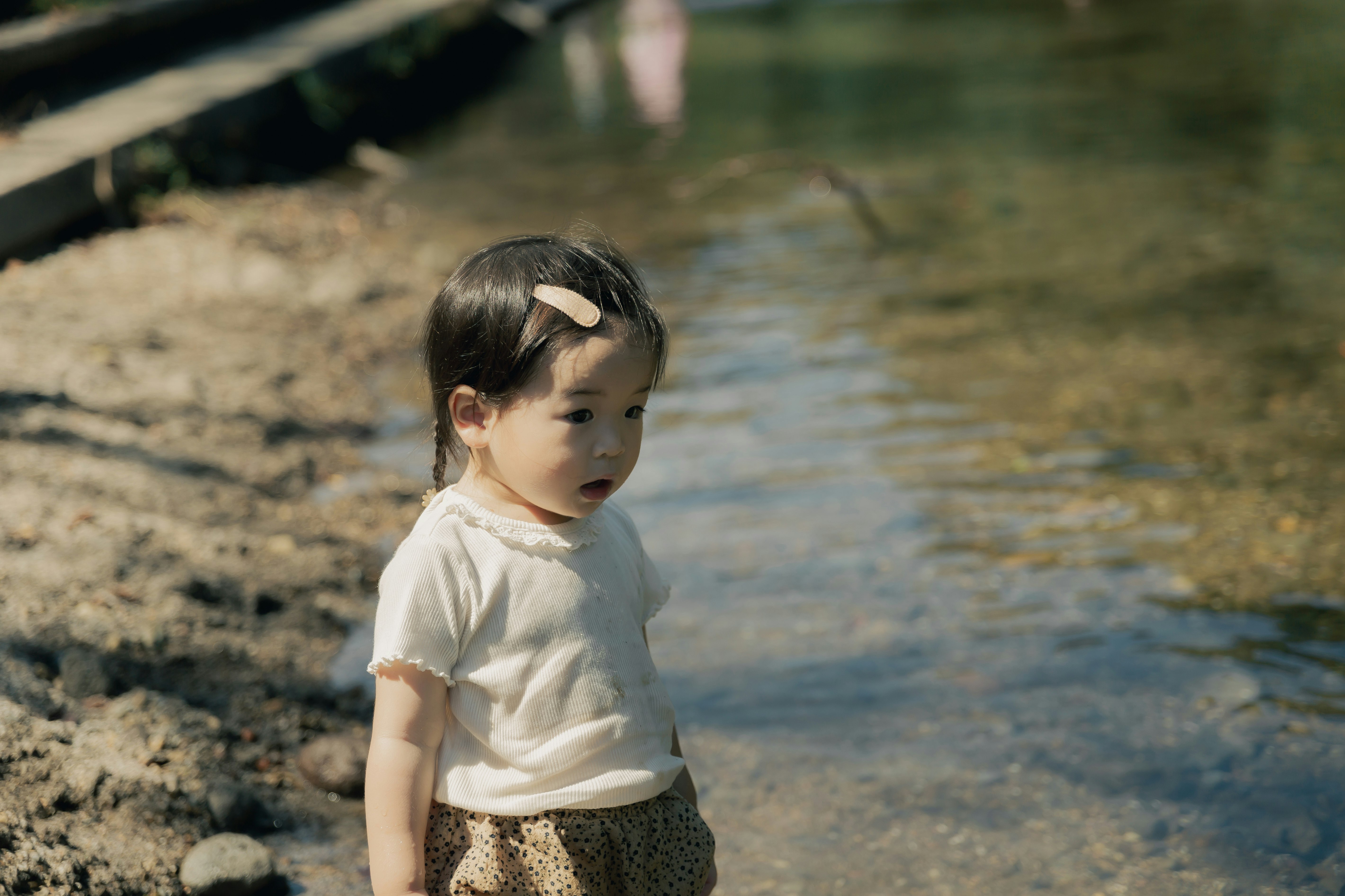 young child standing by a riverbank