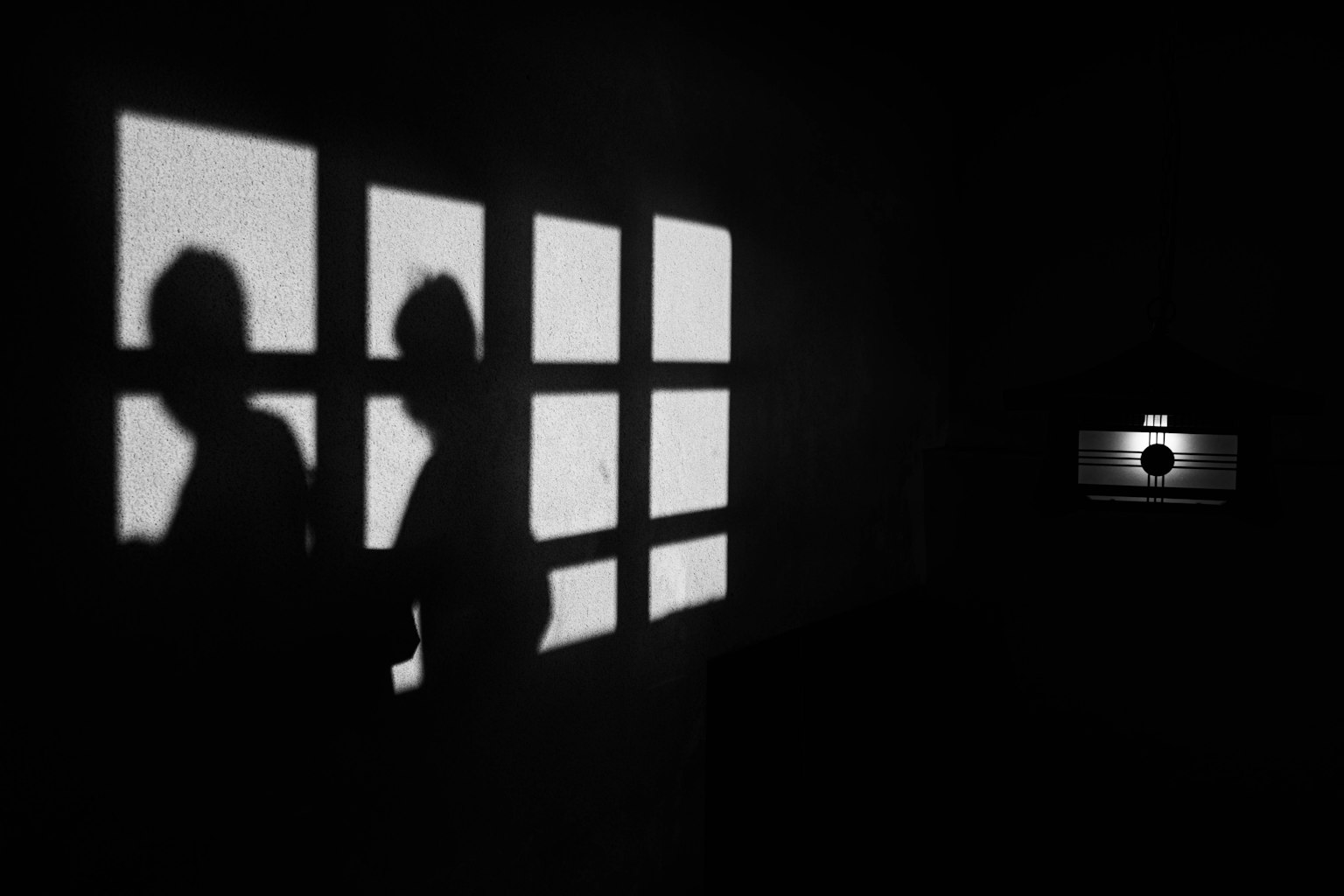 Siluetas de personas contra un fondo oscuro con sombras de ventana