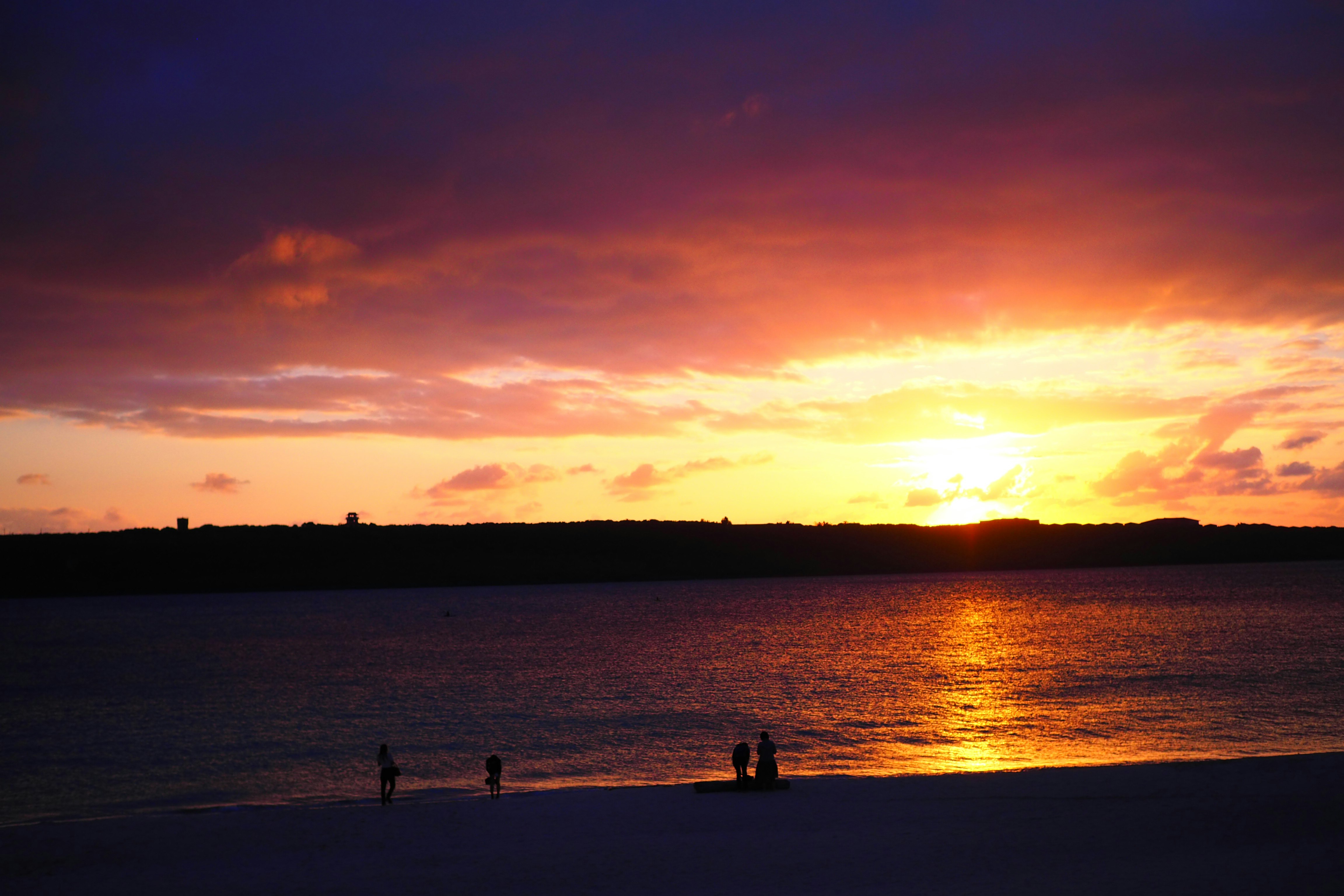 夕日に照らされる海辺の砂浜と人影