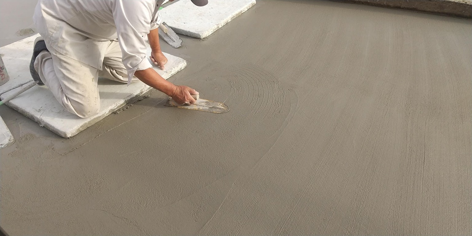 Travailleur nivelant la surface en béton avec une truelle