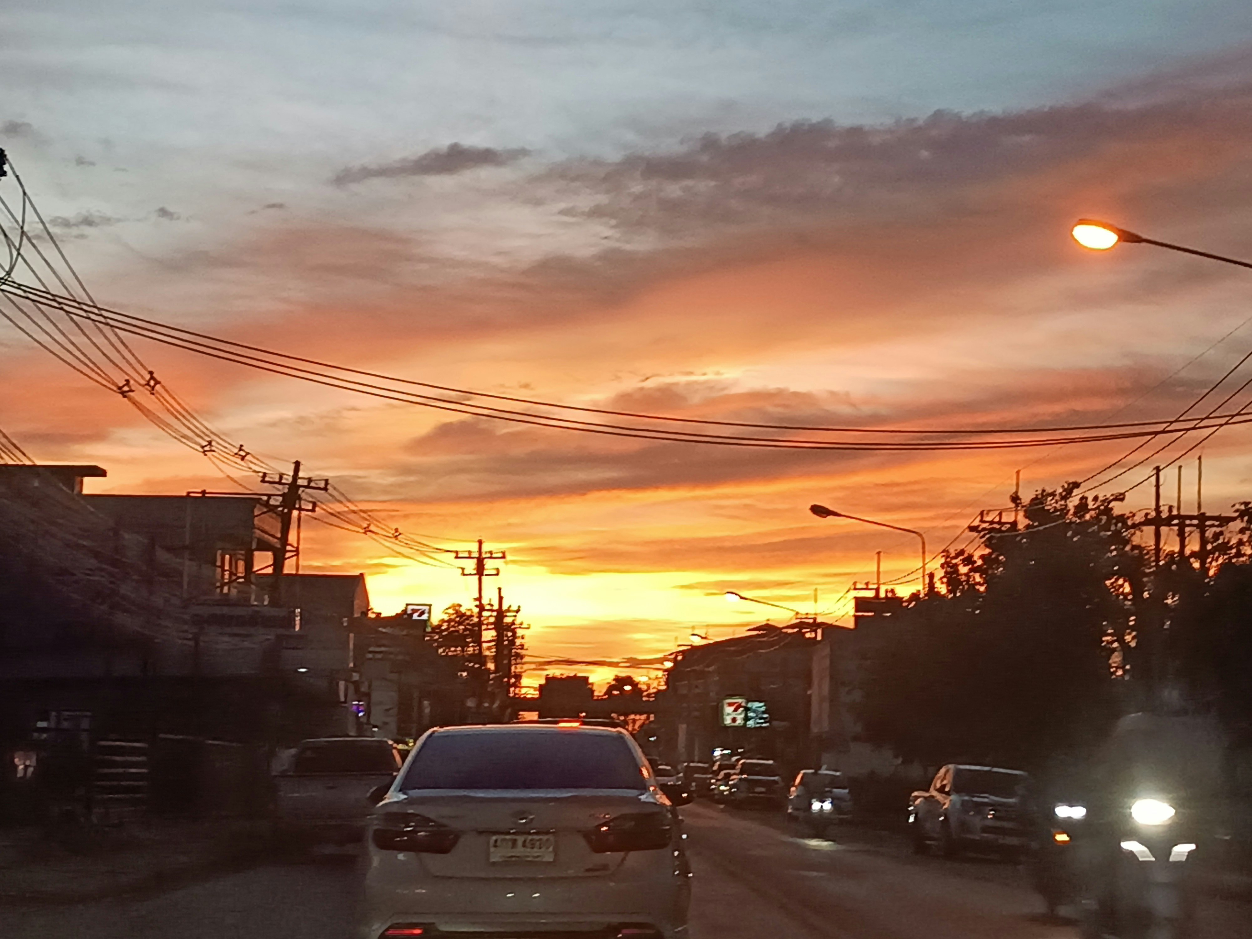 夕暮れの街道を走る車と電線のある風景