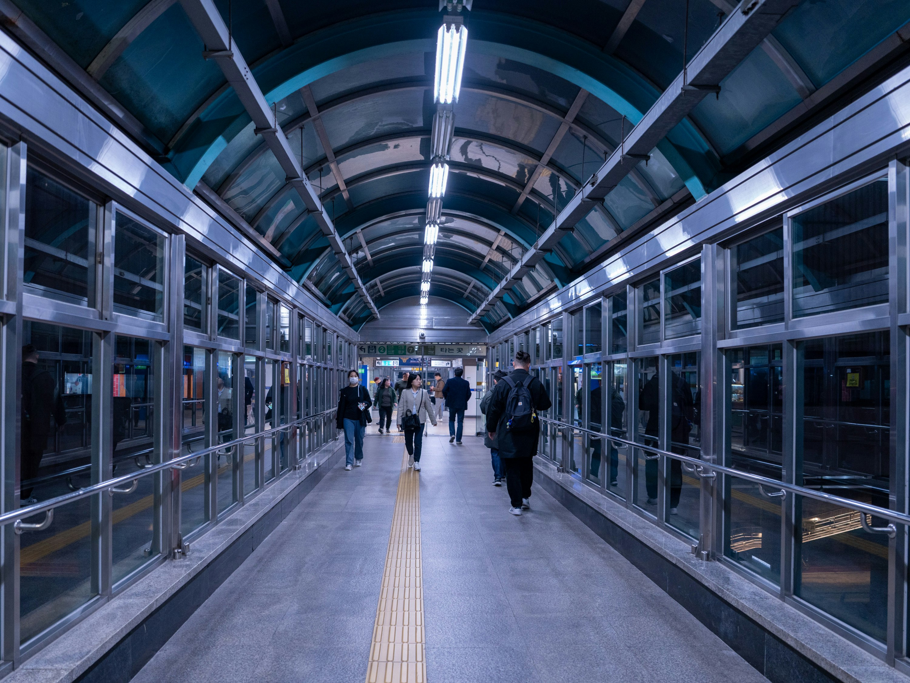 couloir de gare avec passerelle vitrée et voyageurs