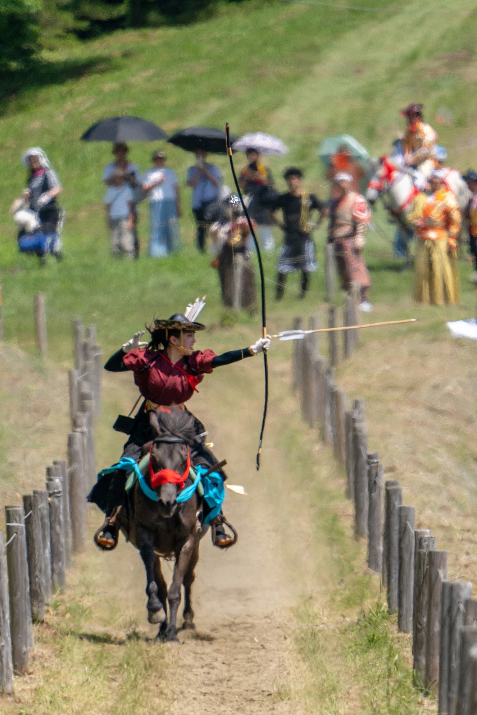 Un arciere a cavallo che mira a una freccia durante una competizione tradizionale con spettatori sullo sfondo