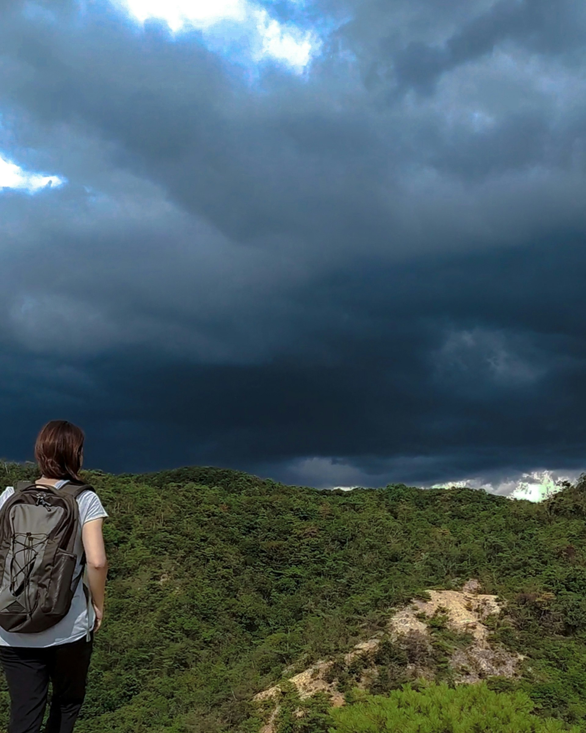 雨雲が迫る山の稜線と登山者の後ろ姿