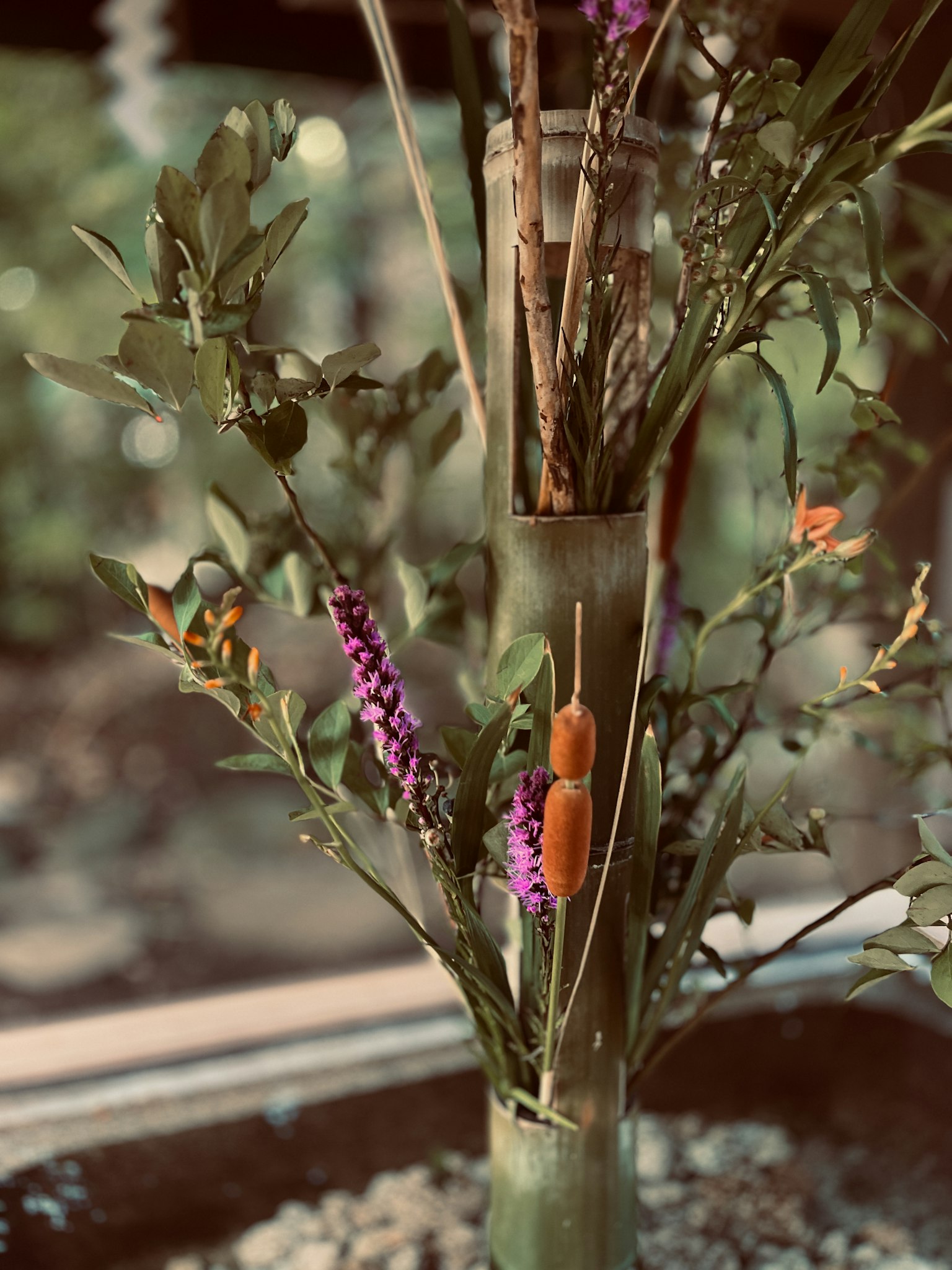 Fleurs colorées et feuilles disposées dans un vase en bambou