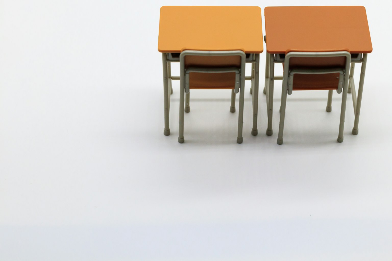 Due tavoli arancioni con sedie disposti in uno stile minimalista