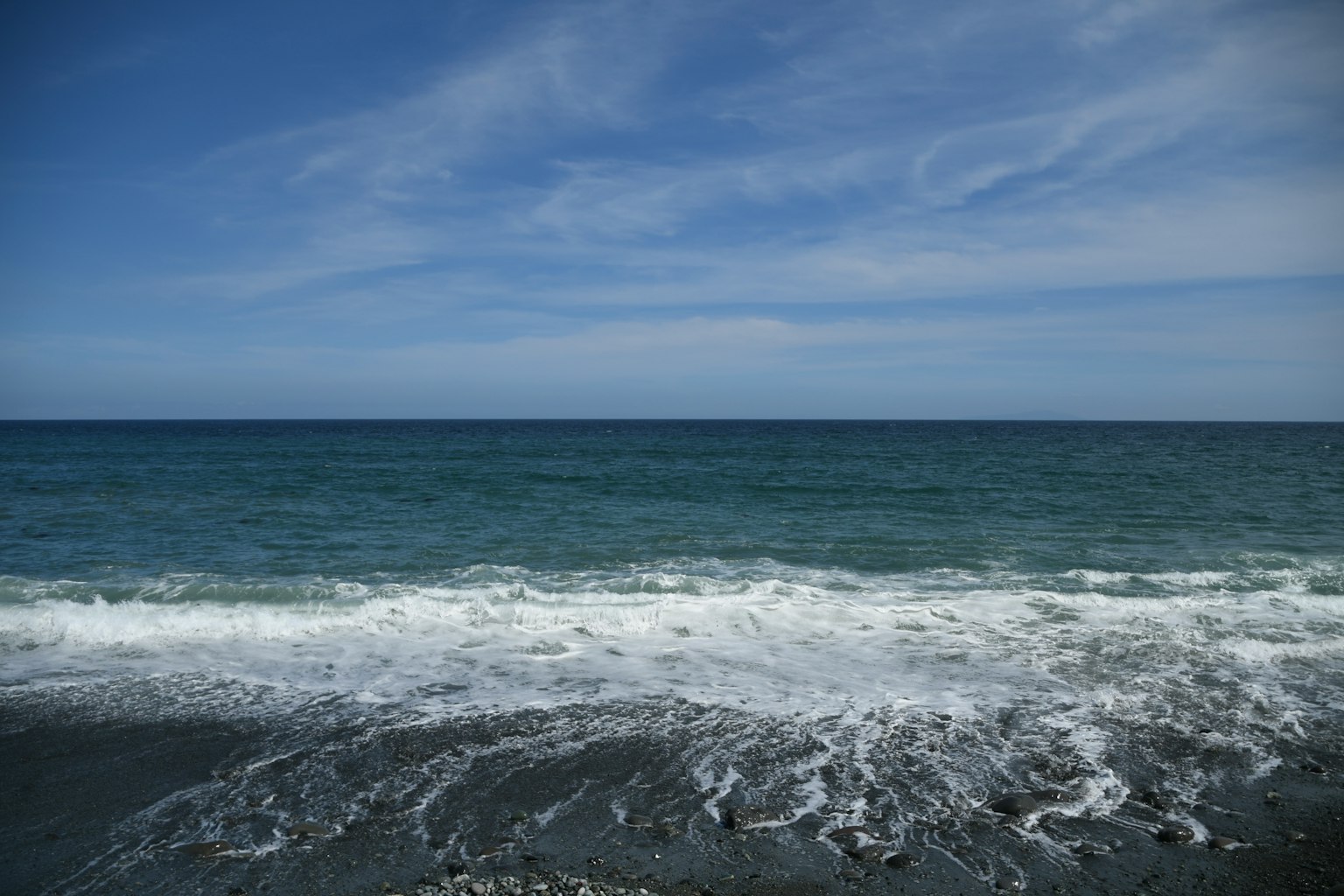 A serene view of a blue ocean with white waves