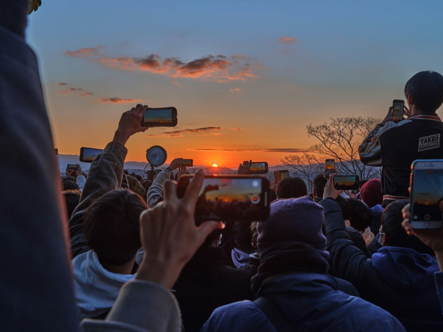 Crowd holding smartphones to capture a sunset