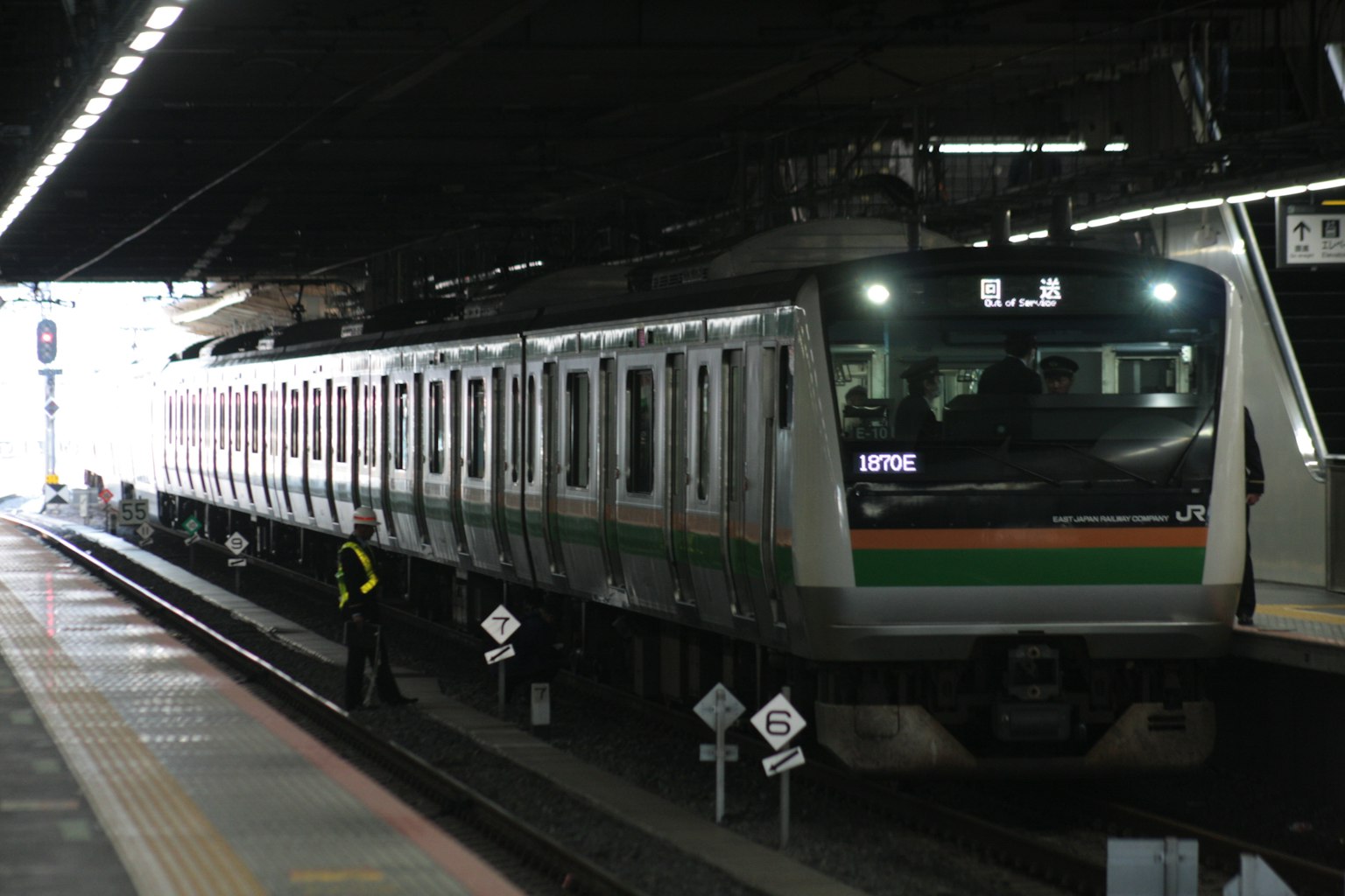 Kereta di stasiun dengan desain hijau dan putih serta petugas stasiun