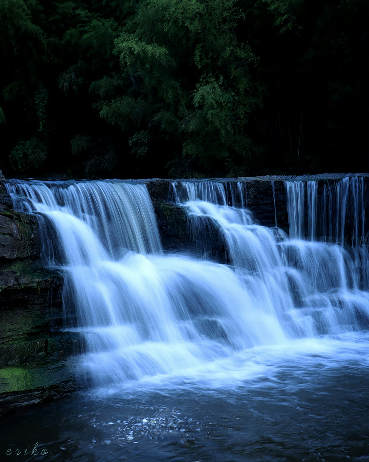 Air terjun yang indah mengalir di lingkungan gelap