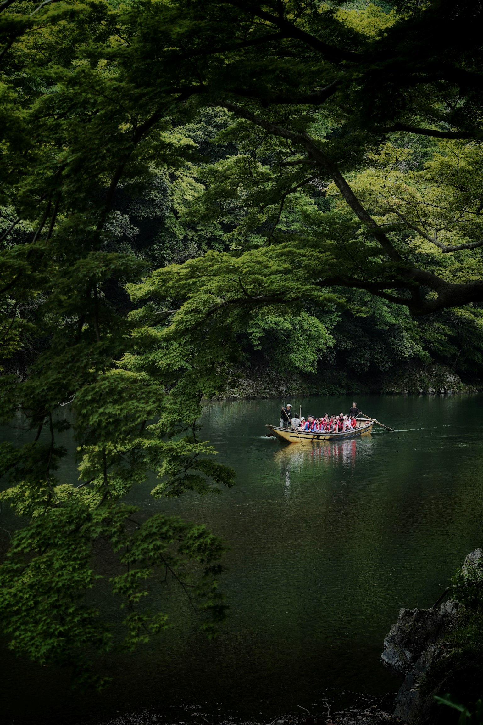 Persone in una barca su un lago tranquillo circondato da alberi verdi lussureggianti
