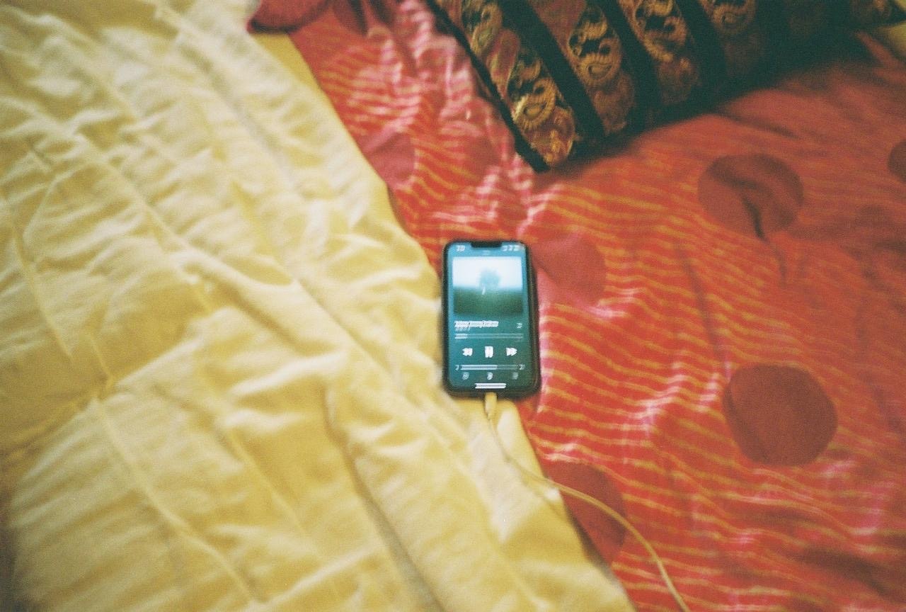 ベッドの上に置かれたスマートフォンとカラフルな枕