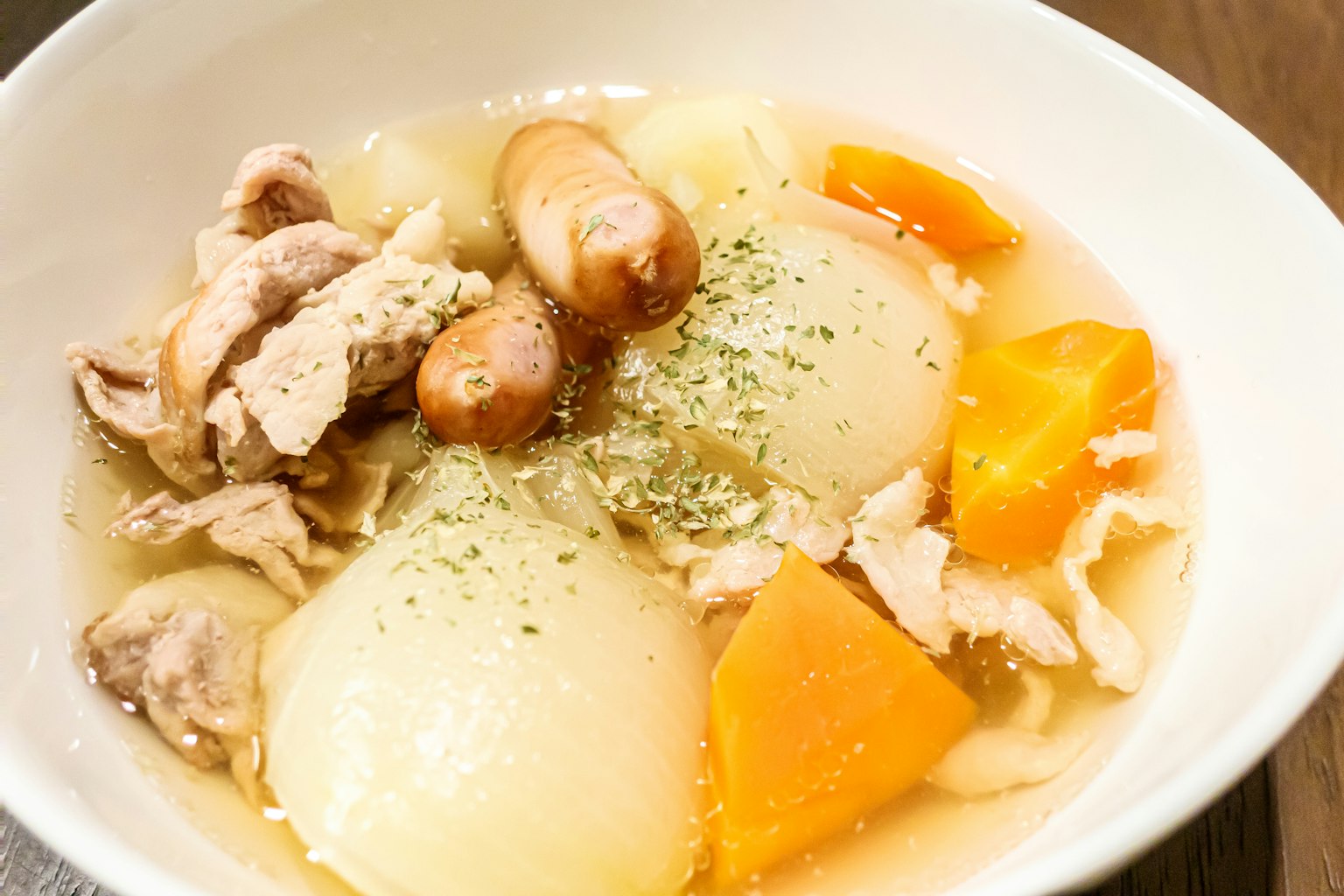 Hühnersuppe mit Gemüse, süßem Kürbis, weißem Rettich und grünen Kräutern als Garnitur