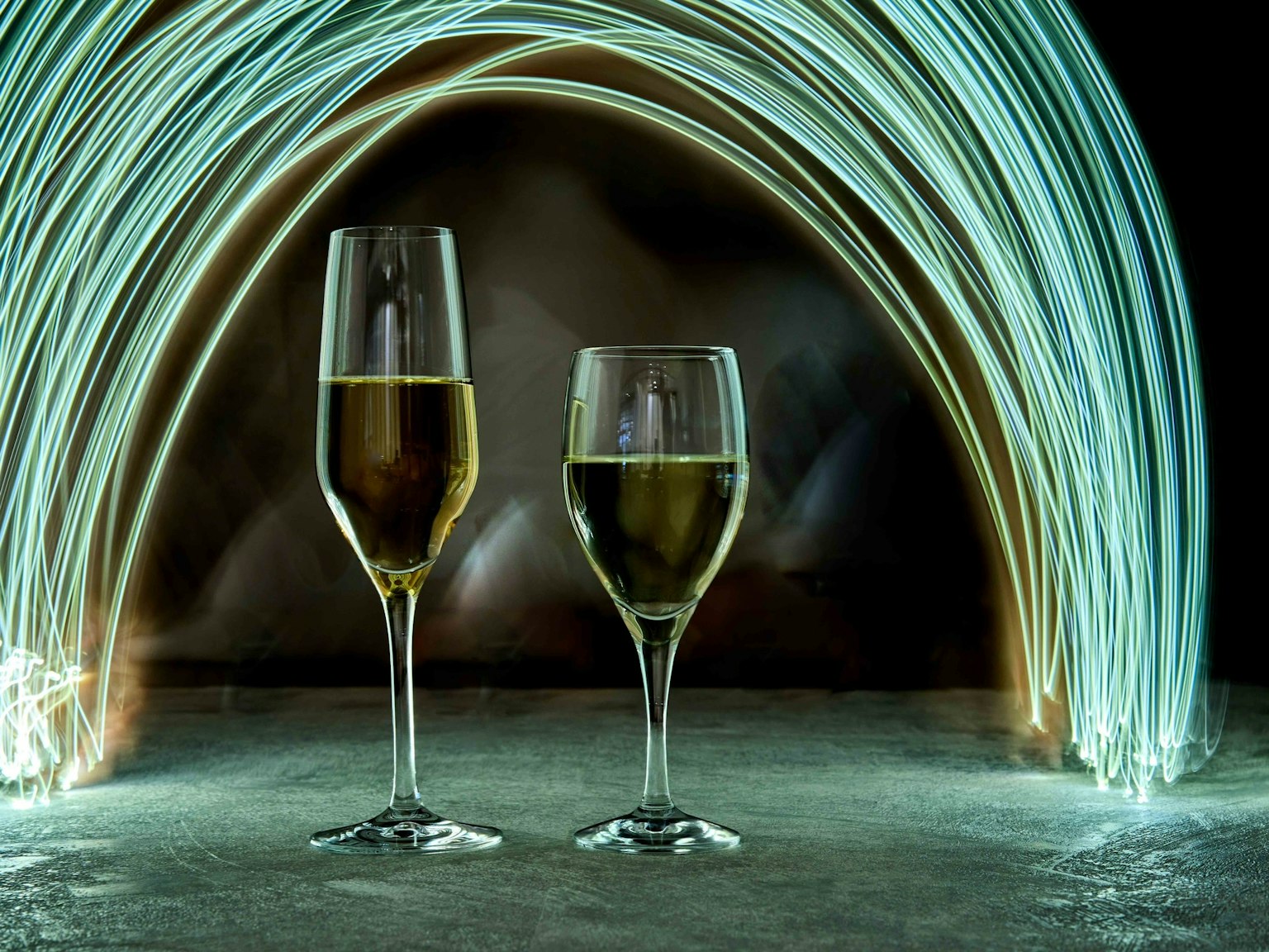 Due bicchieri di vino davanti a un arco di luce teal