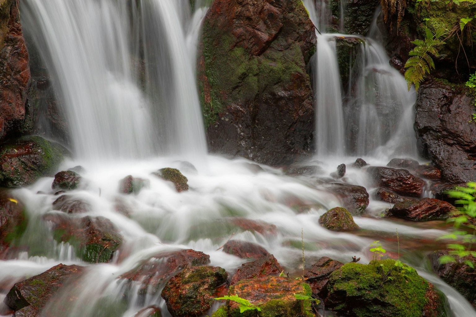 Pemandangan indah air terjun mengalir di atas batu
