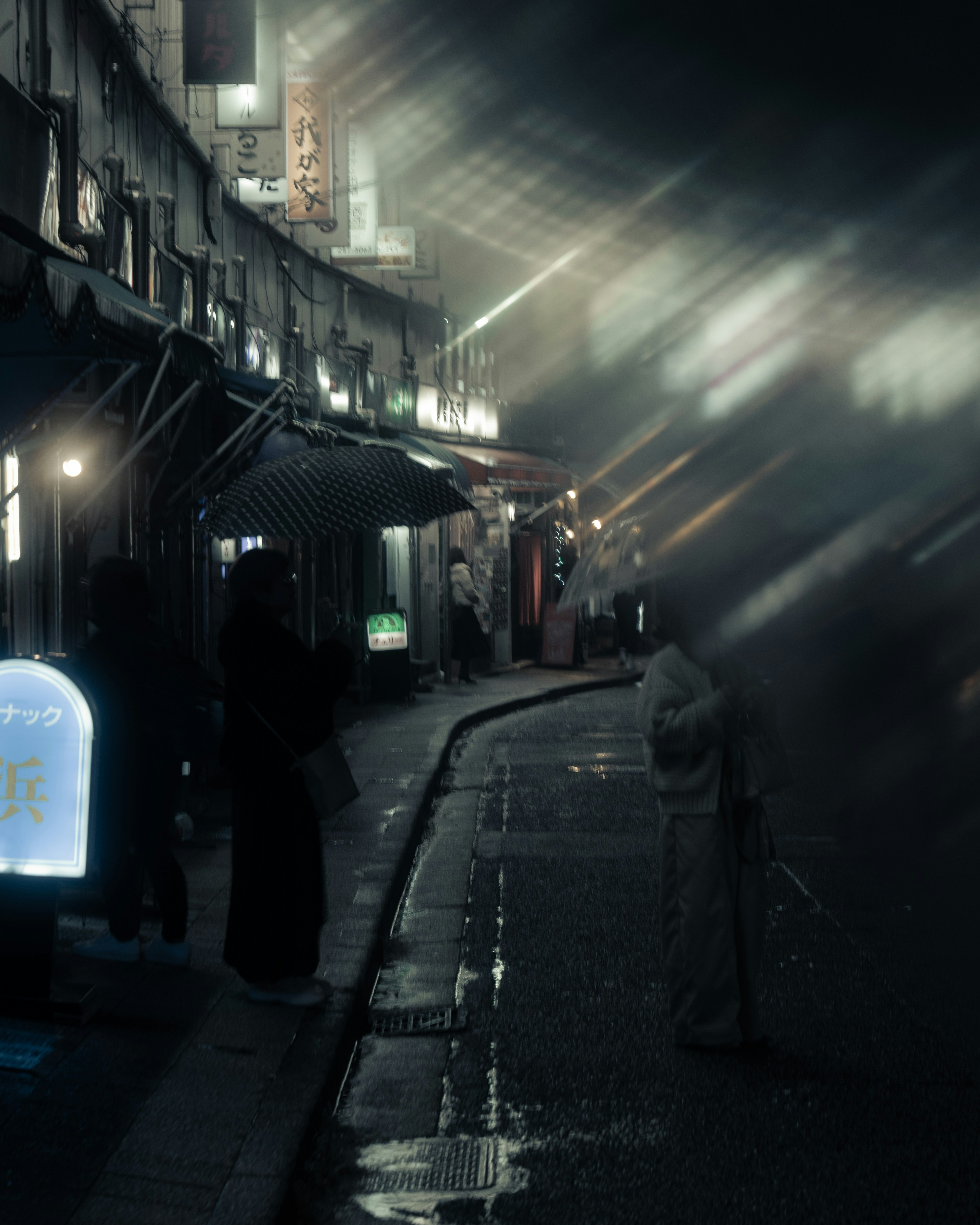 Nighttime shopping alley with lanterns and storefront signs after rain
