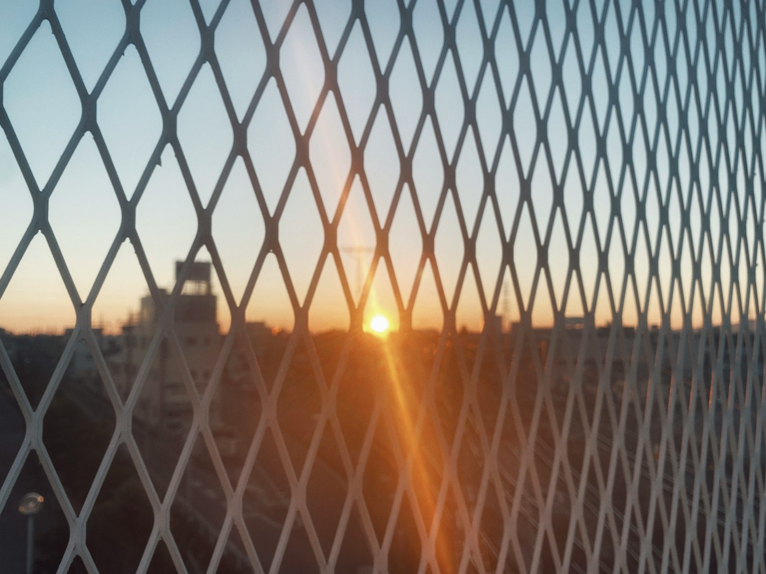 Sonnenuntergang durch einen rautenförmigen Zaun betrachtet
