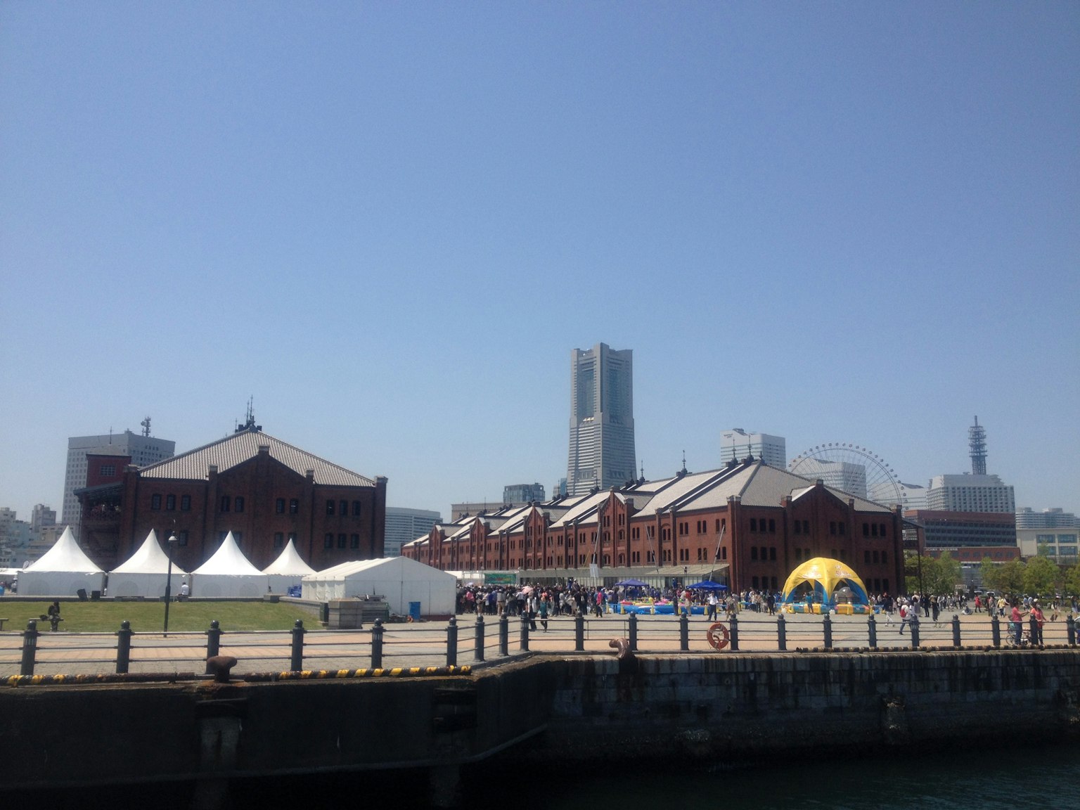 Yokohama Red Brick Warehouse with modern buildings in the background clear blue sky and people at an outdoor event