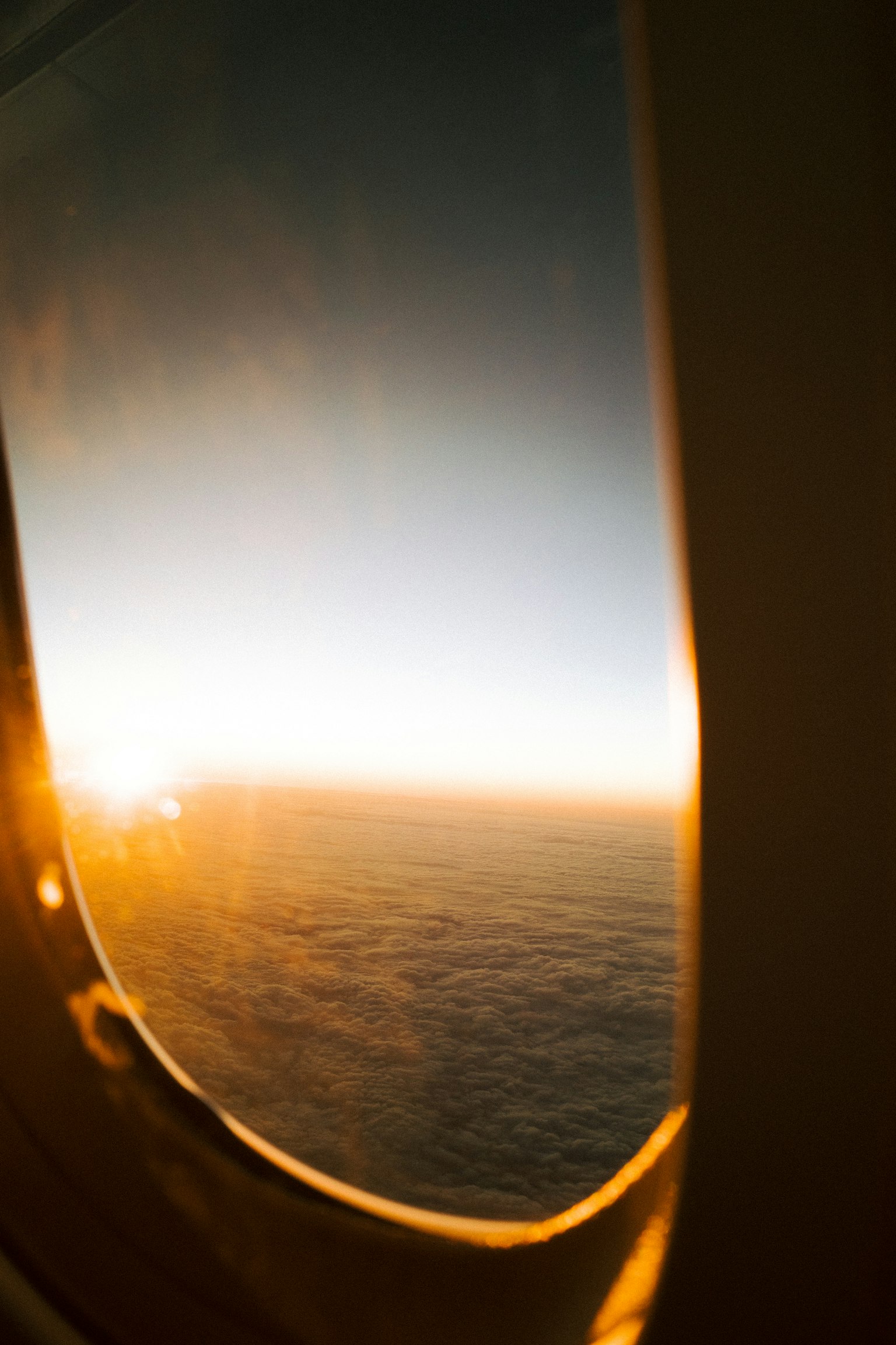 飛行機の窓から見える夕日の景色と雲海