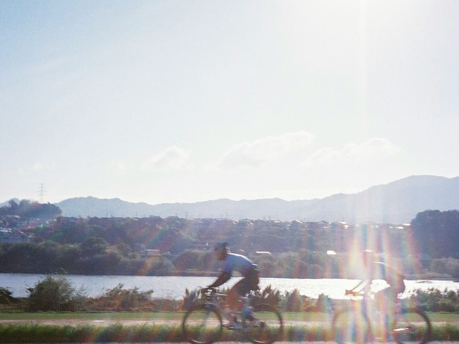 自転車に乗る二人のサイクリストが川沿いの道を走る風景