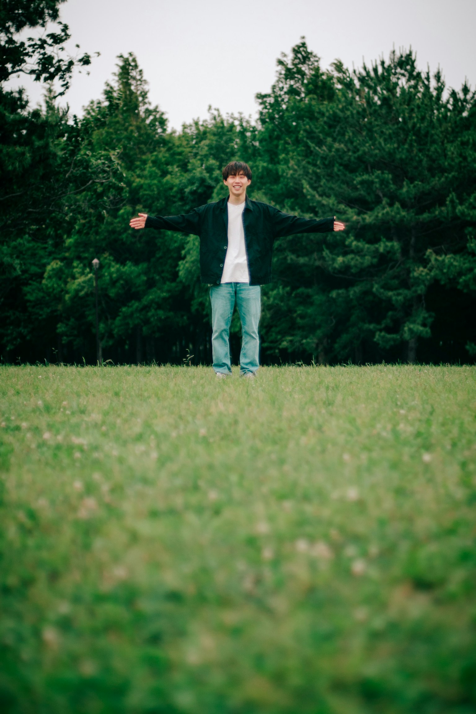 Man standing in a green field with arms outstretched