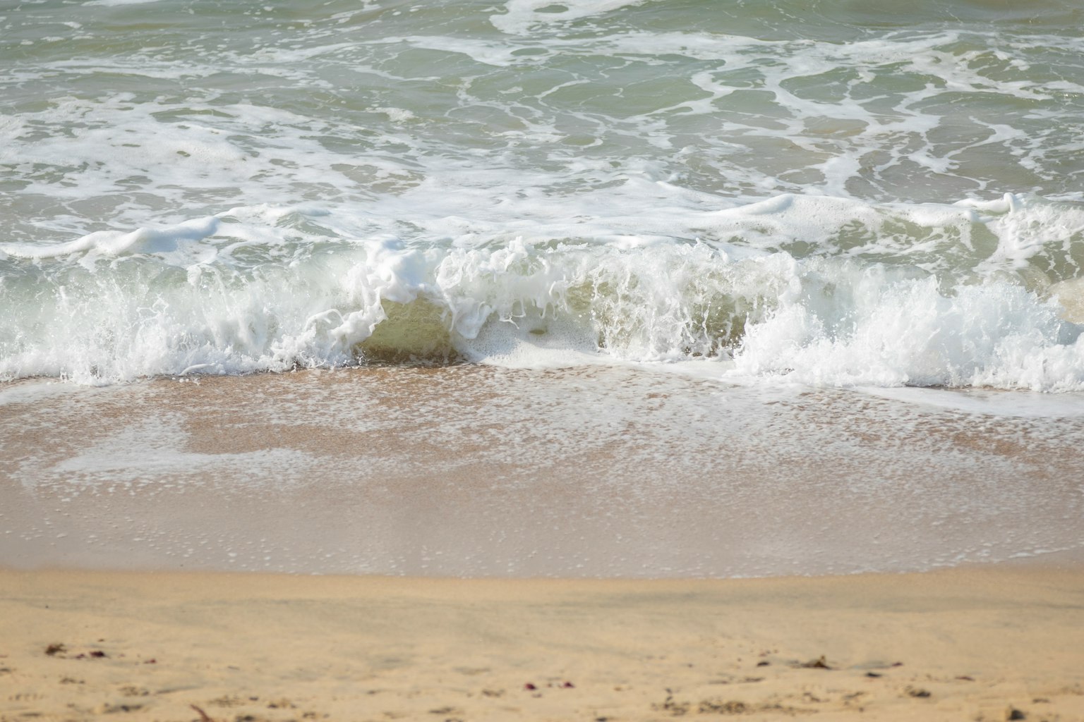 Gelombang yang menghantam pantai berpasir