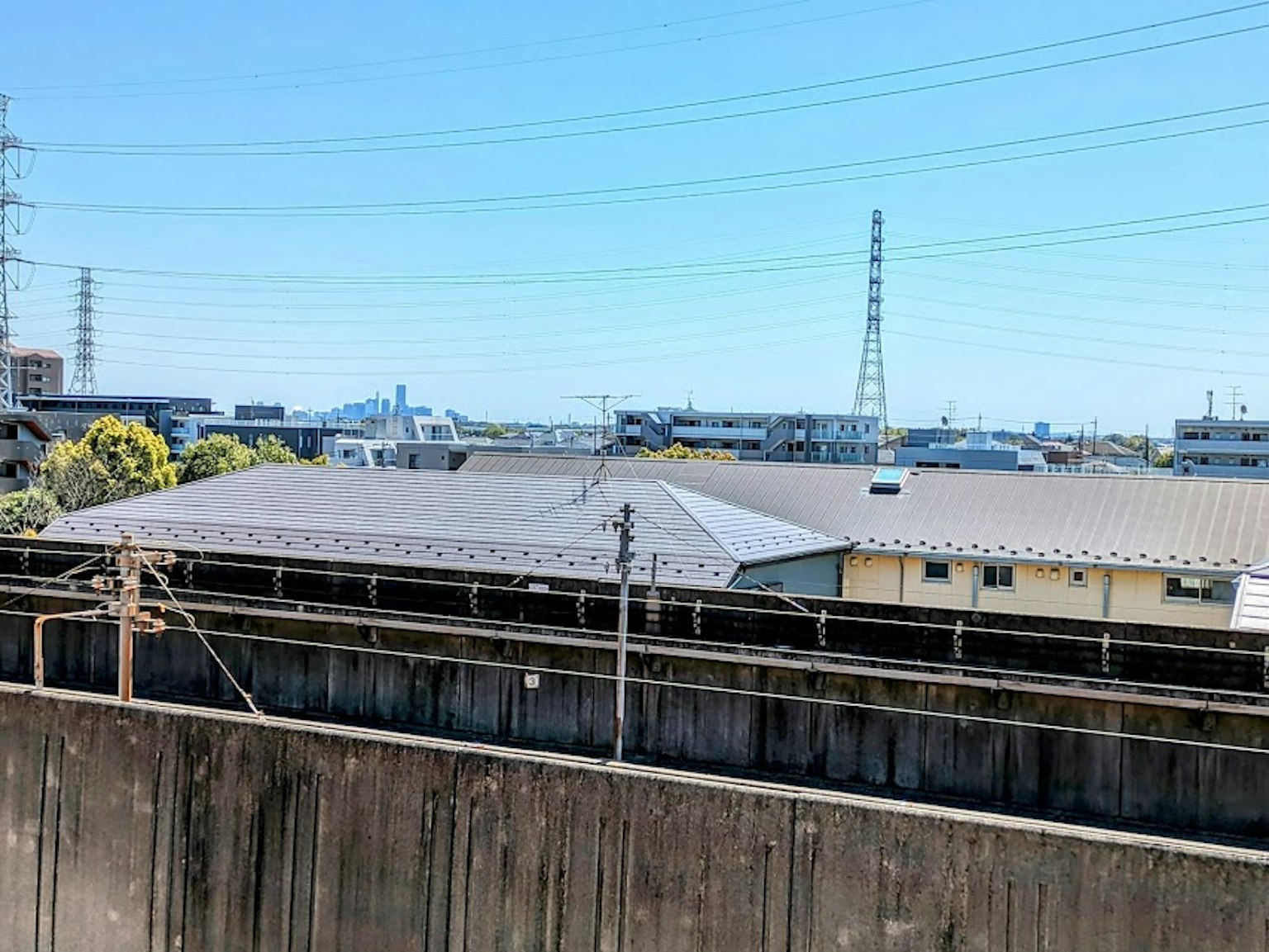 Paysage urbain sous un ciel bleu avec des toits et des lignes électriques