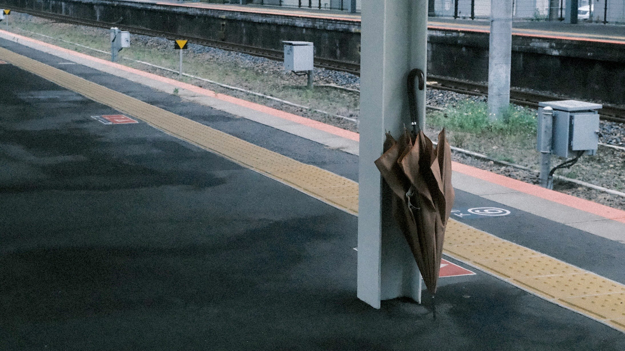 駅のホームで柱に掛けられた掲示板と線路の見える風景