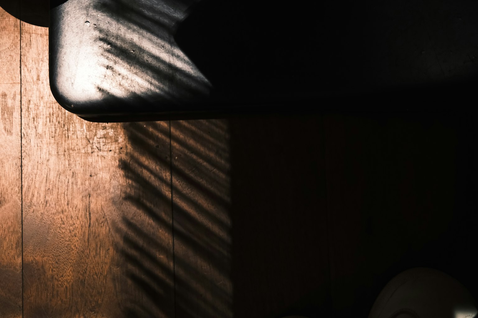 나무 바닥에 드리워진 그림자와 검은 물체의 일부