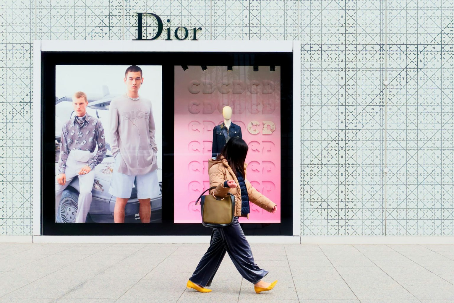 คนเดินอยู่หน้าร้าน Dior ที่มีการจัดแสดงแฟชั่น