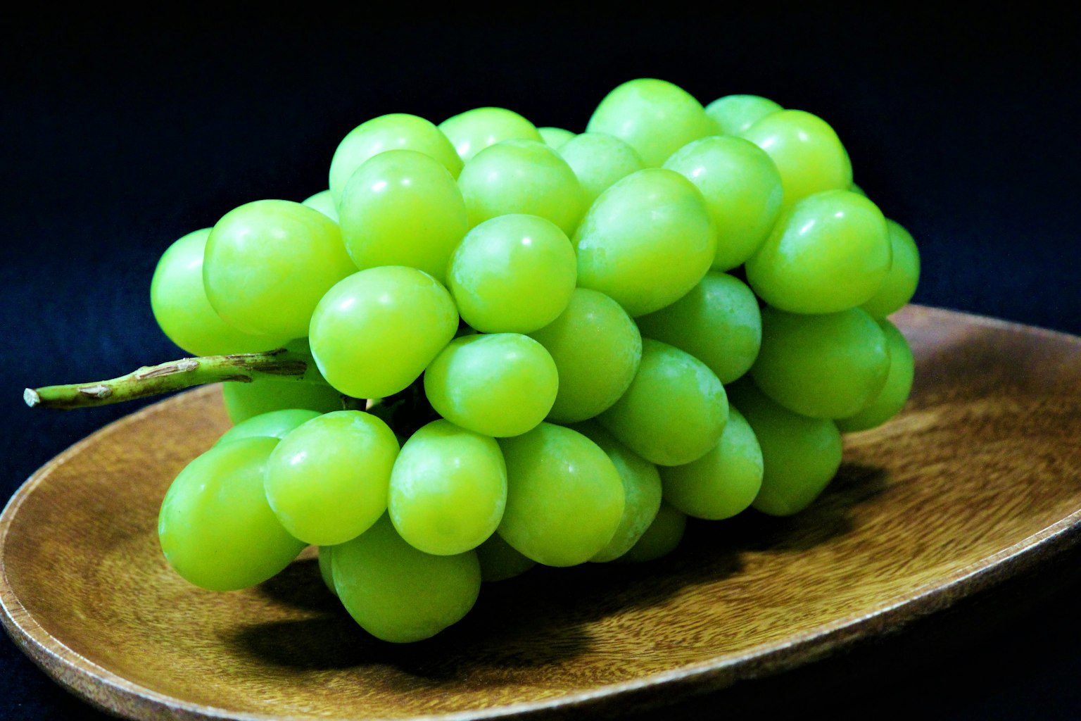 A bunch of green grapes on a wooden plate