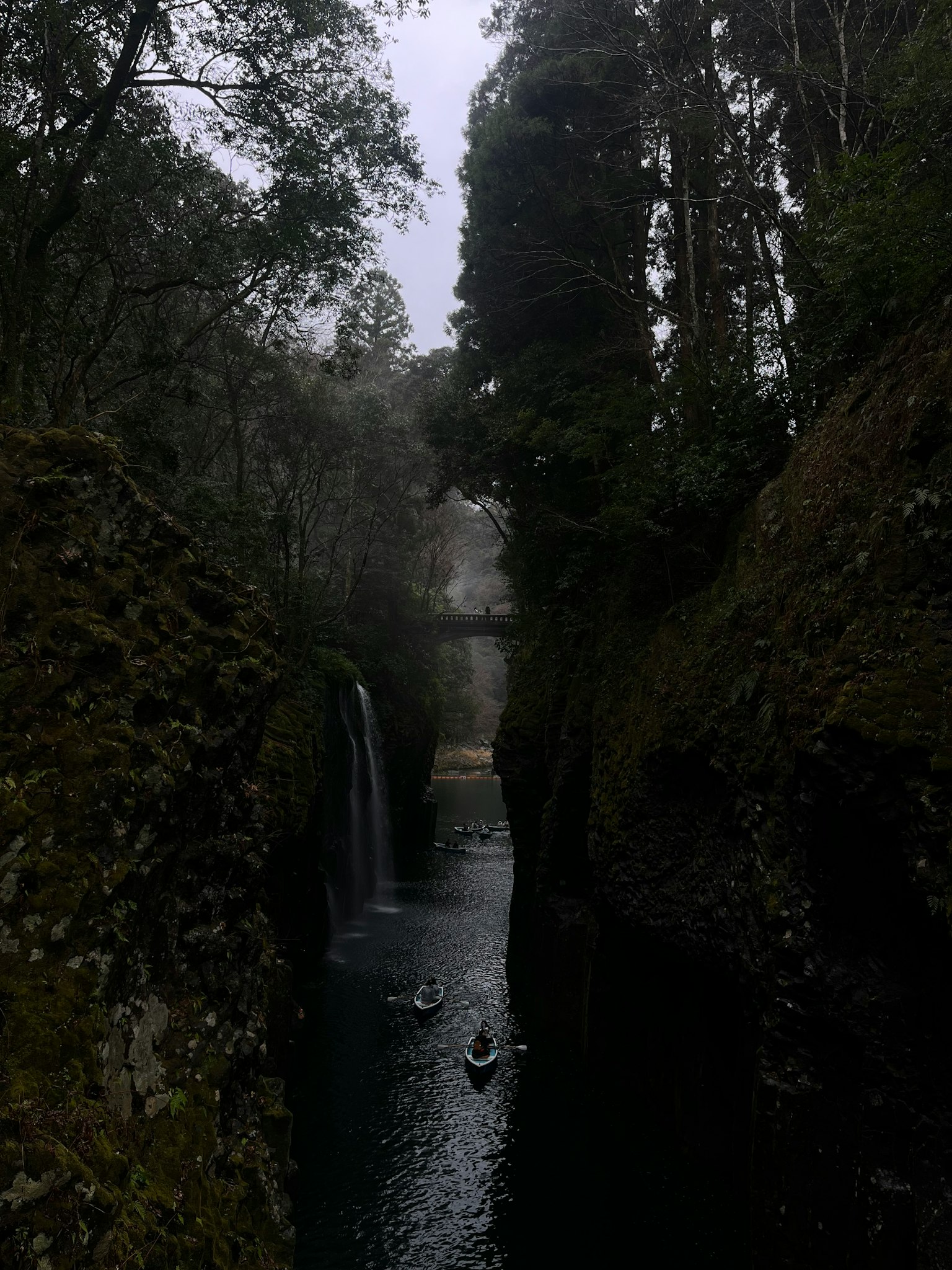 Cañón brumoso con una cascada y kayakistas