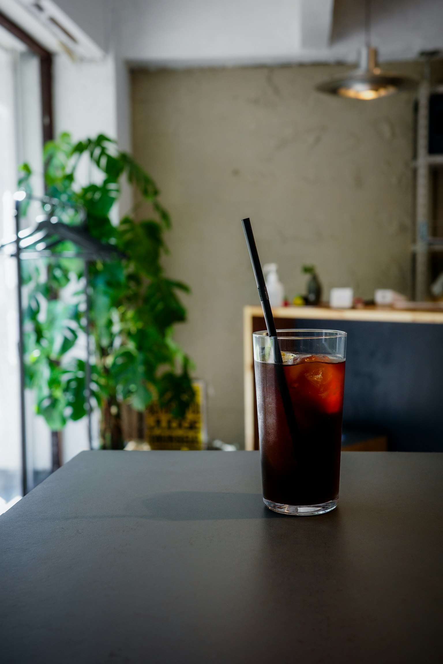 テーブルの上に置かれたアイスコーヒーのグラスと緑の植物
