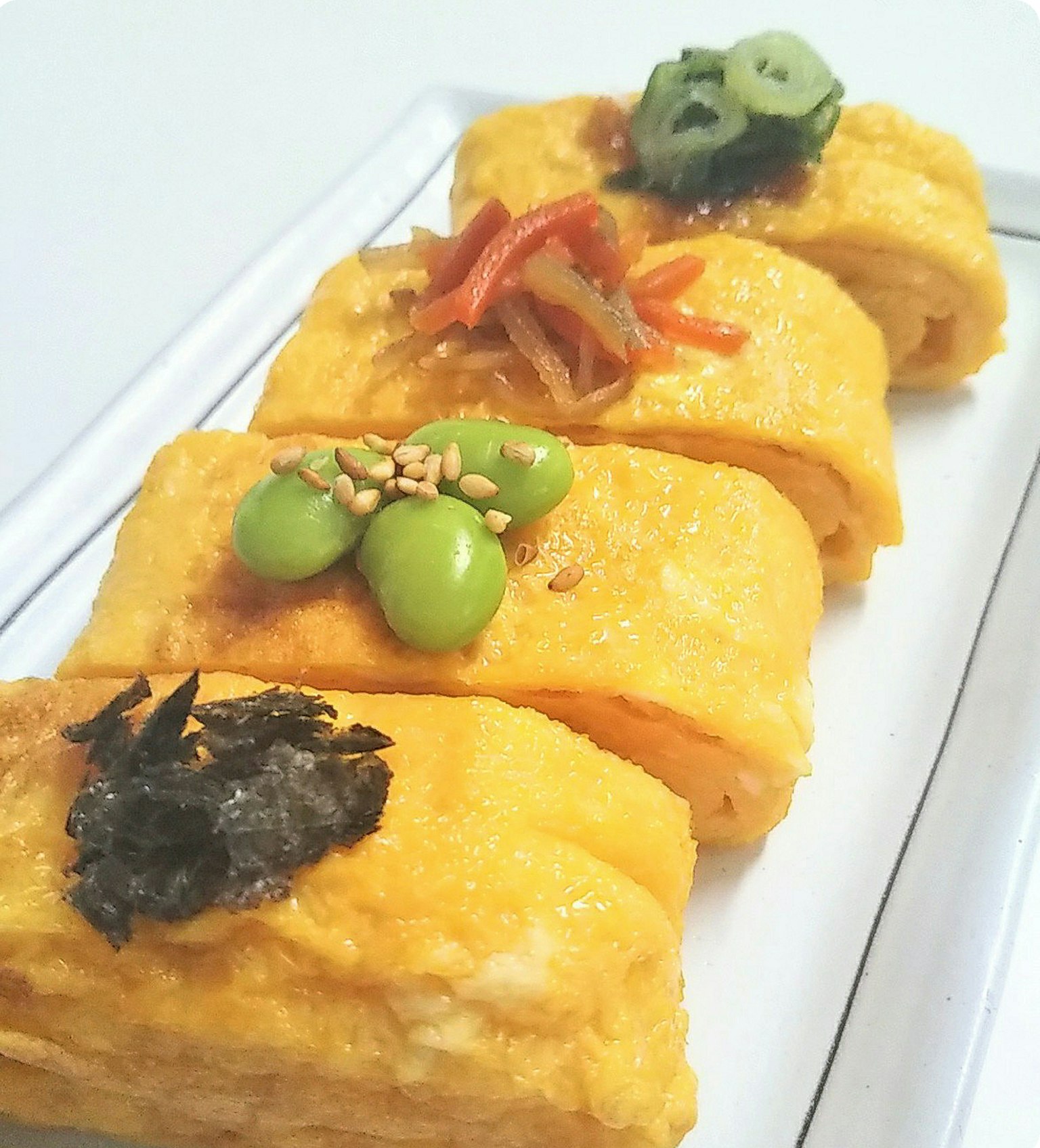 Vielfältiges Tamagoyaki mit bunten Belägen, darunter Frühlingszwiebeln, rote Paprika, Bohnen und Algen