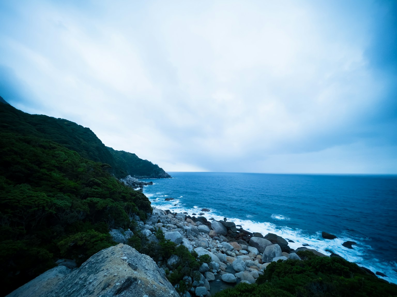 Pemandangan pantai dengan lautan biru dan langit mendung