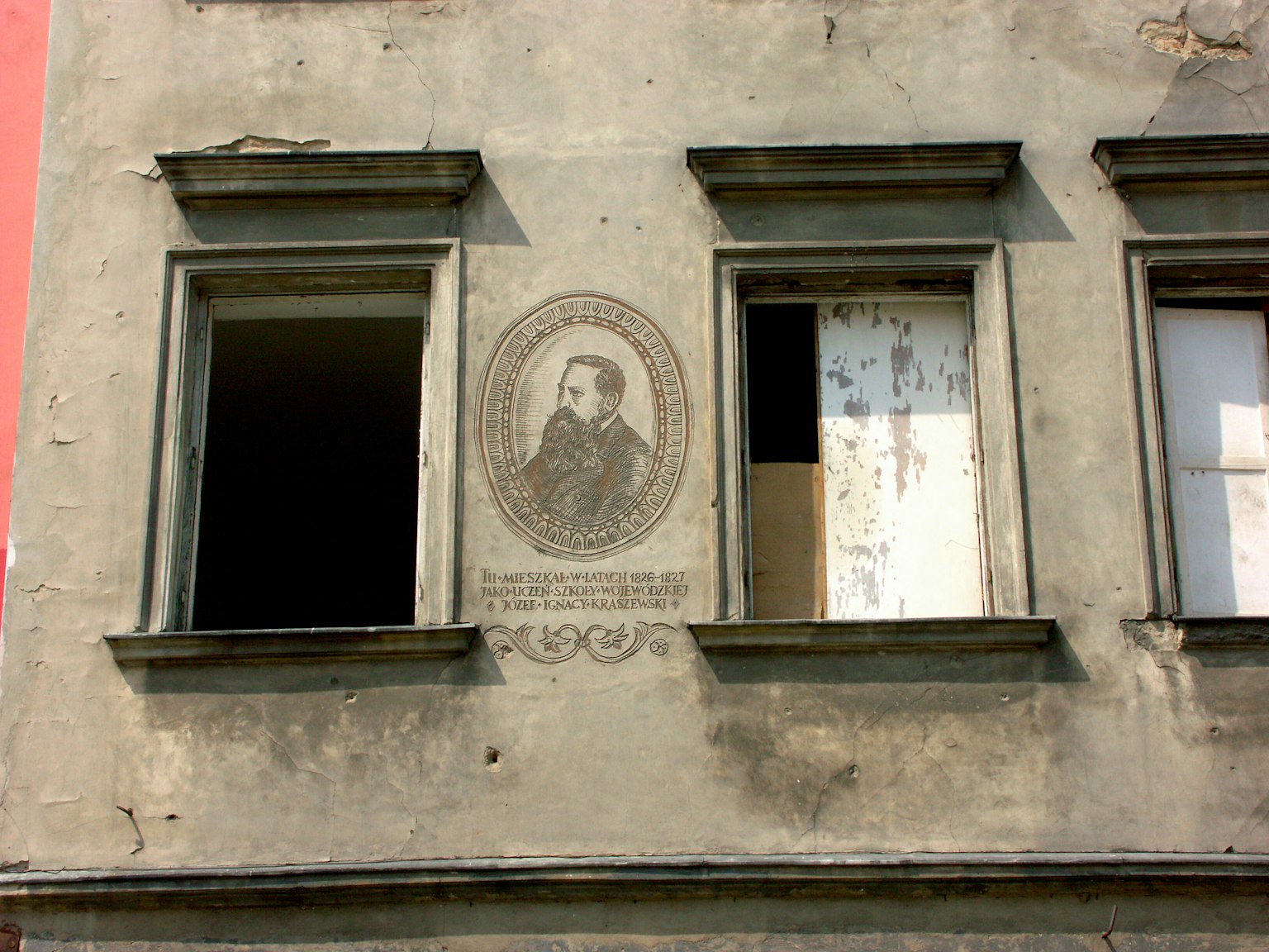 Ritratto su un muro di un edificio logoro con finestre aperte