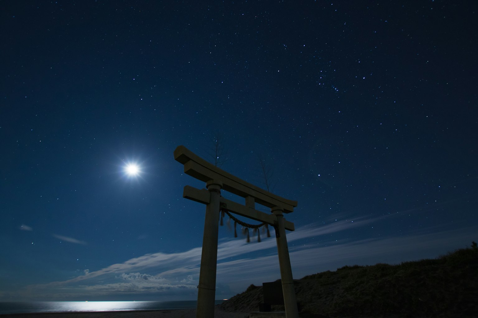 Torii sous un ciel étoilé avec une lune brillante